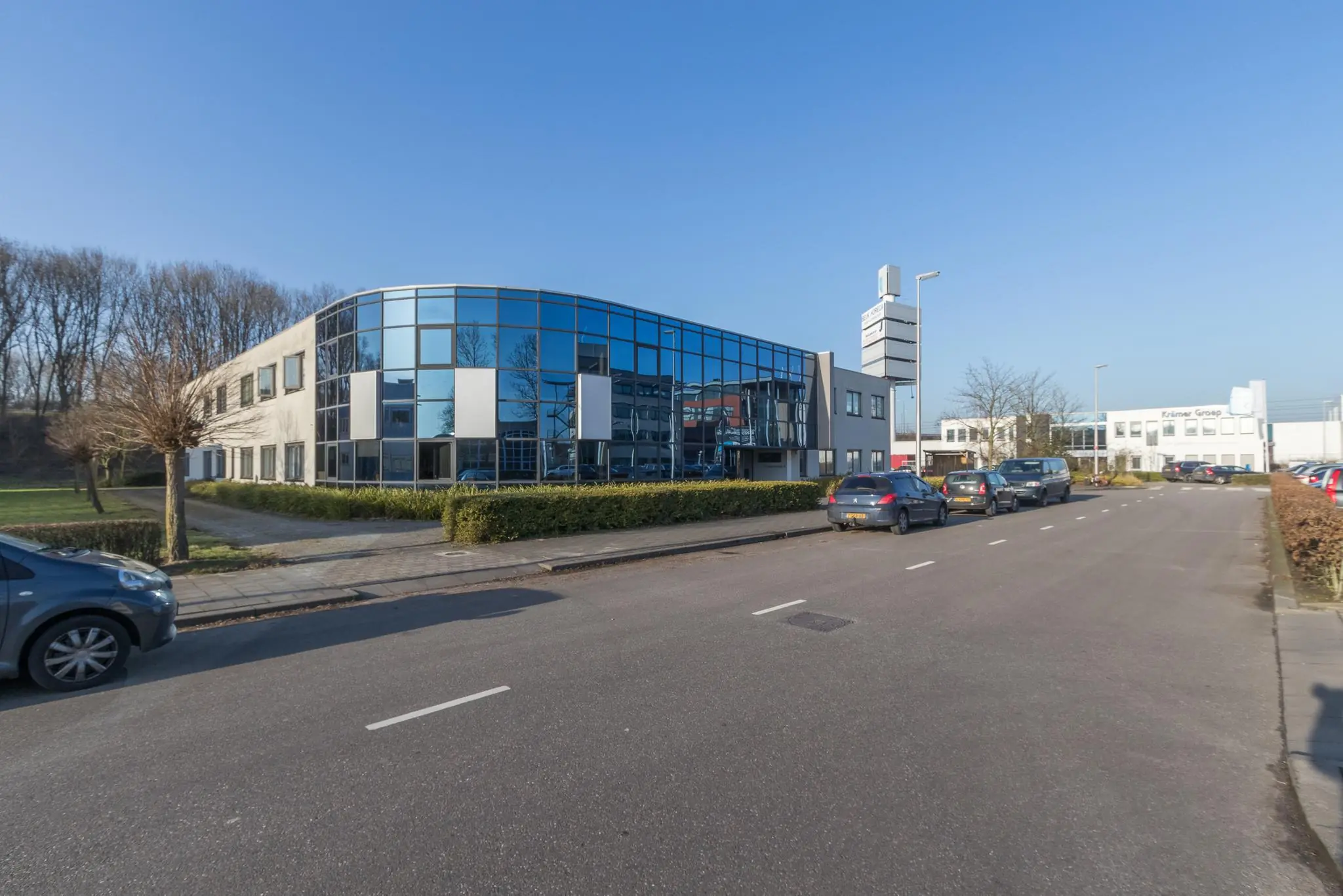 Modern kantoorpand met glazen gevel aan de Computerweg, gelegen aan een rustige straat met geparkeerde auto's.