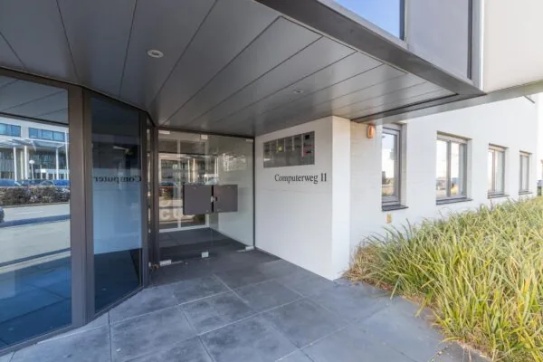 Ingang van een modern kantoorpand aan de Computerweg 11 met glazen deur en brievenbussen.