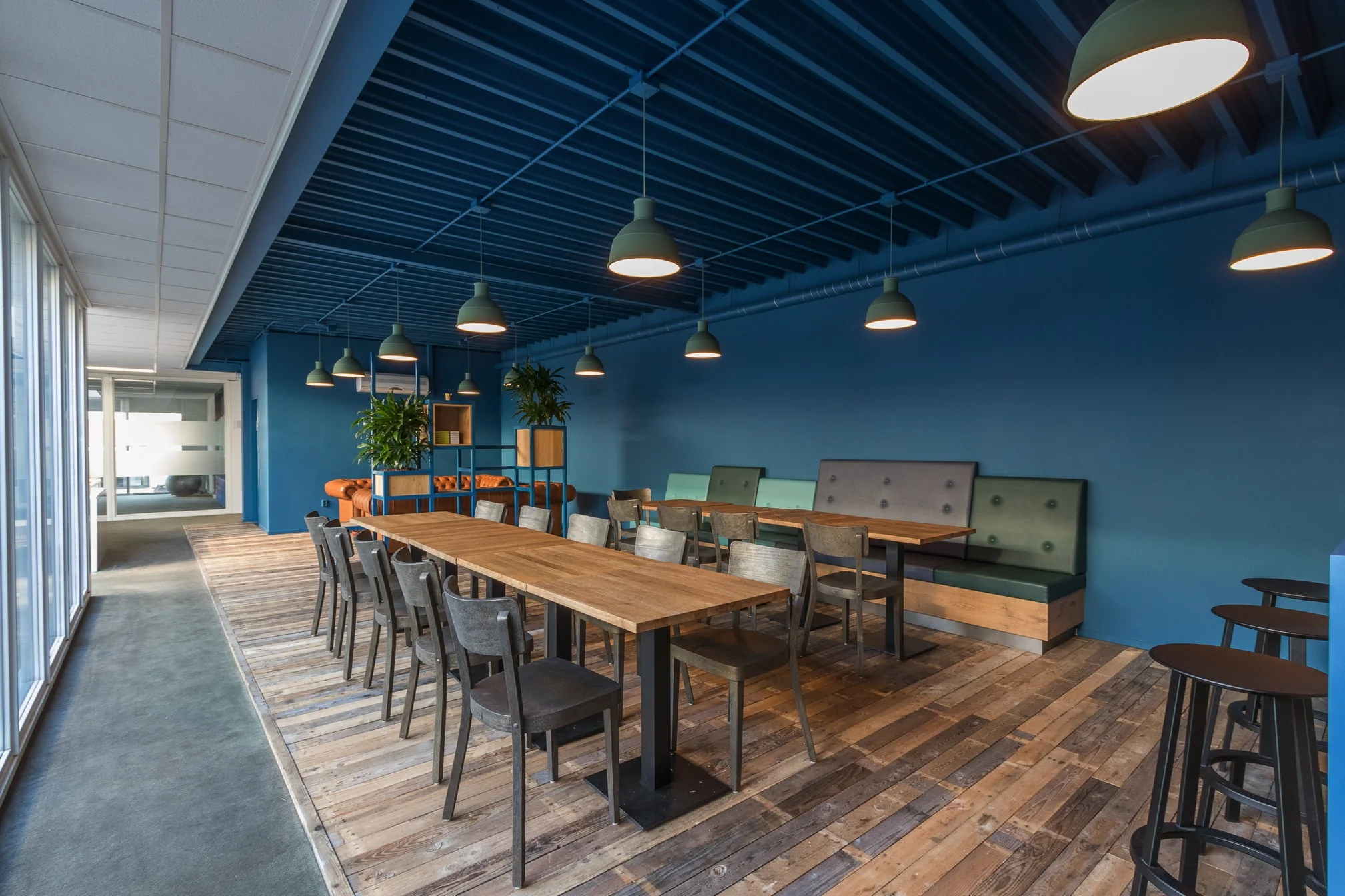 Moderne, sfeervolle kantoorkantine aan de Computerweg met houten vloeren, blauwe muren en hanglampen.