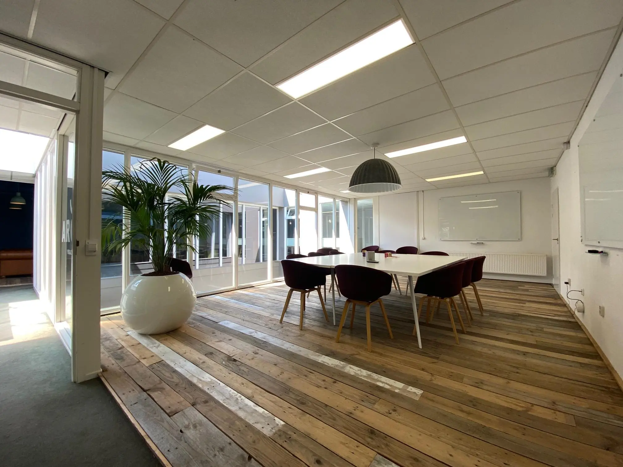 Vergaderruimte aan de Computerweg met een grote tafel, moderne stoelen, houten vloer en veel daglicht.