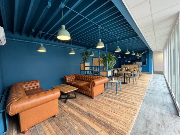 Moderne bedrijfslounge aan de Computerweg met leren banken, houten vloer en een gezamenlijke eethoek.