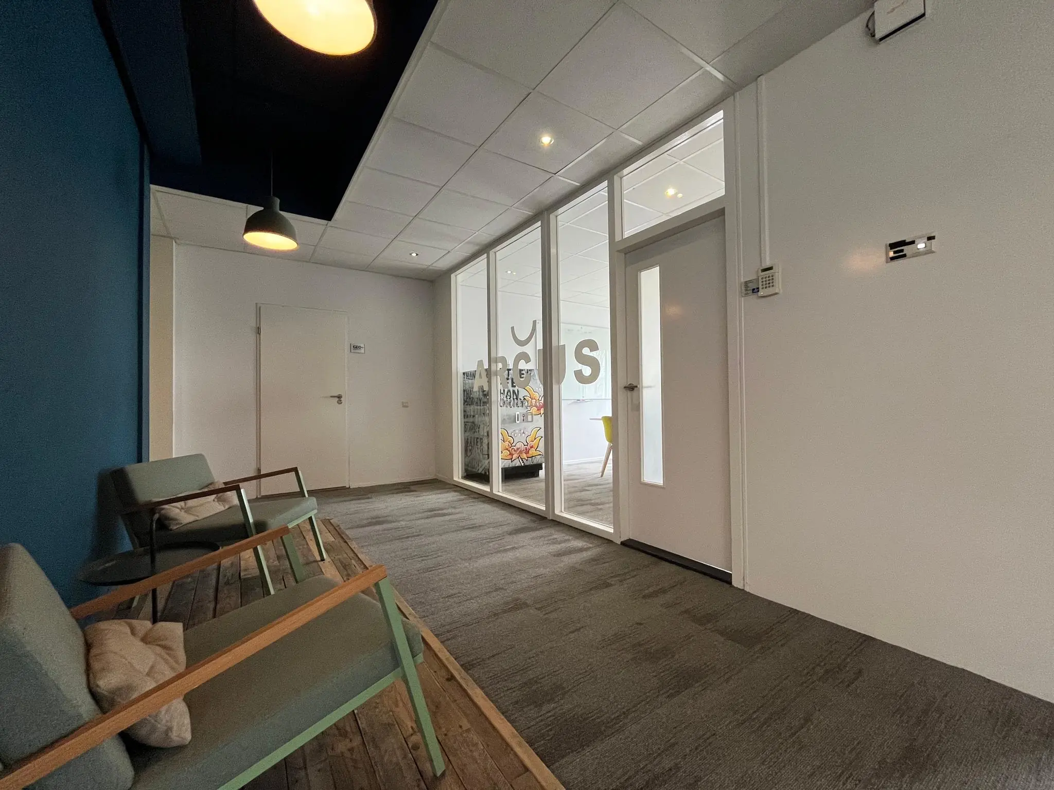 Moderne wachtruimte met stoelen, blauwe muur en uitzicht op een vergaderruimte bij ARGO360 aan de Computerweg.