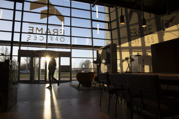 In de entree van Frame Offices aan de Atoomweg schijnt de zon door de glazen gevel terwijl een persoon binnenloopt.