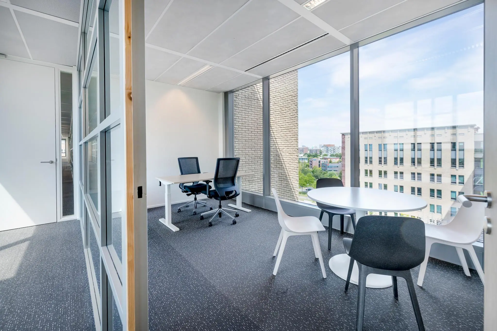 Modern kantoor met werkplekken en vergadertafel aan de Mercatorlaan met uitzicht op omliggende gebouwen.