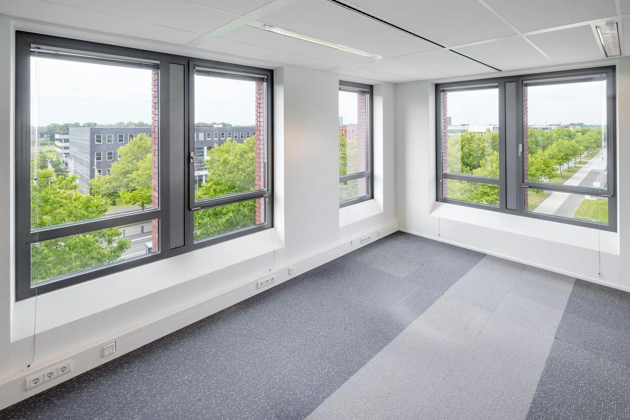 Licht en leeg kantoorruimte met grote ramen aan de Mercatorlaan en uitzicht op een groene, stedelijke omgeving.