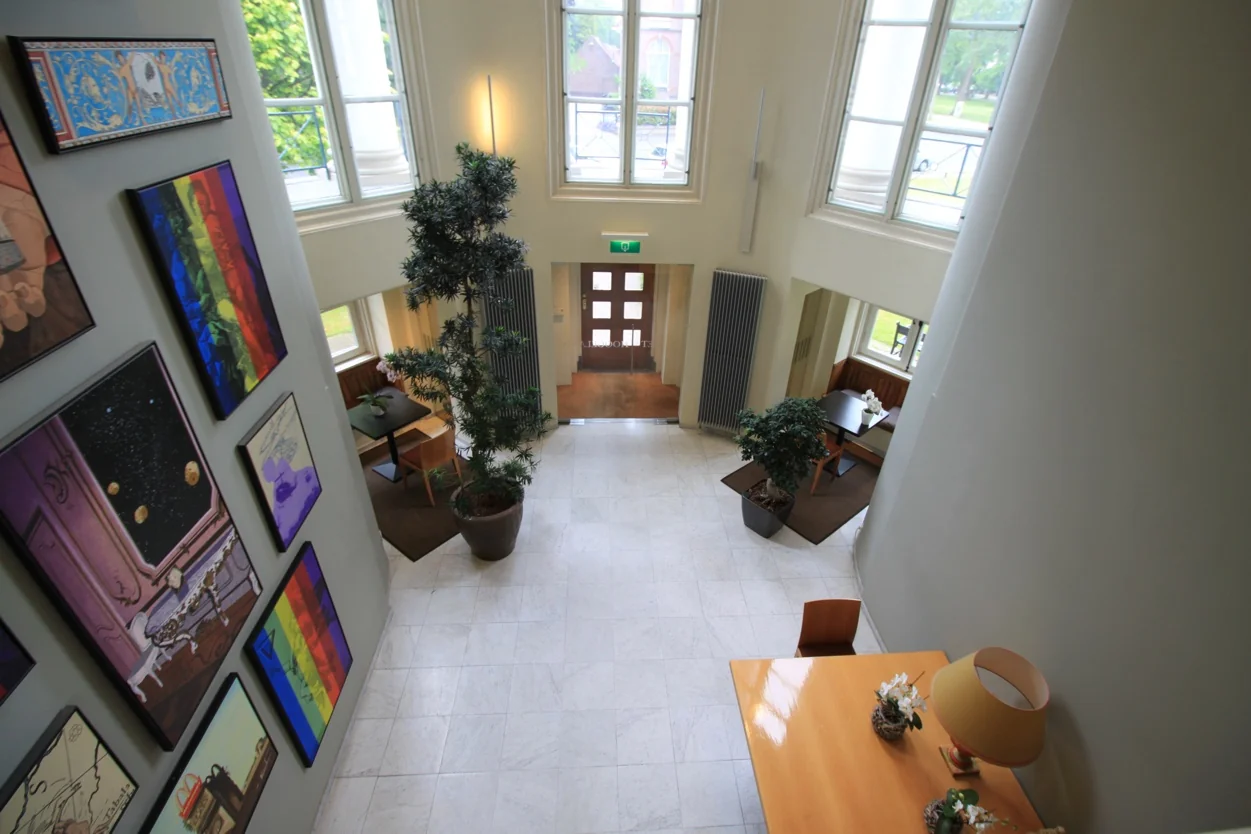 Lichte, moderne hal met hoge ramen, kunst aan de muur en zitplekken bij Museumlaan.