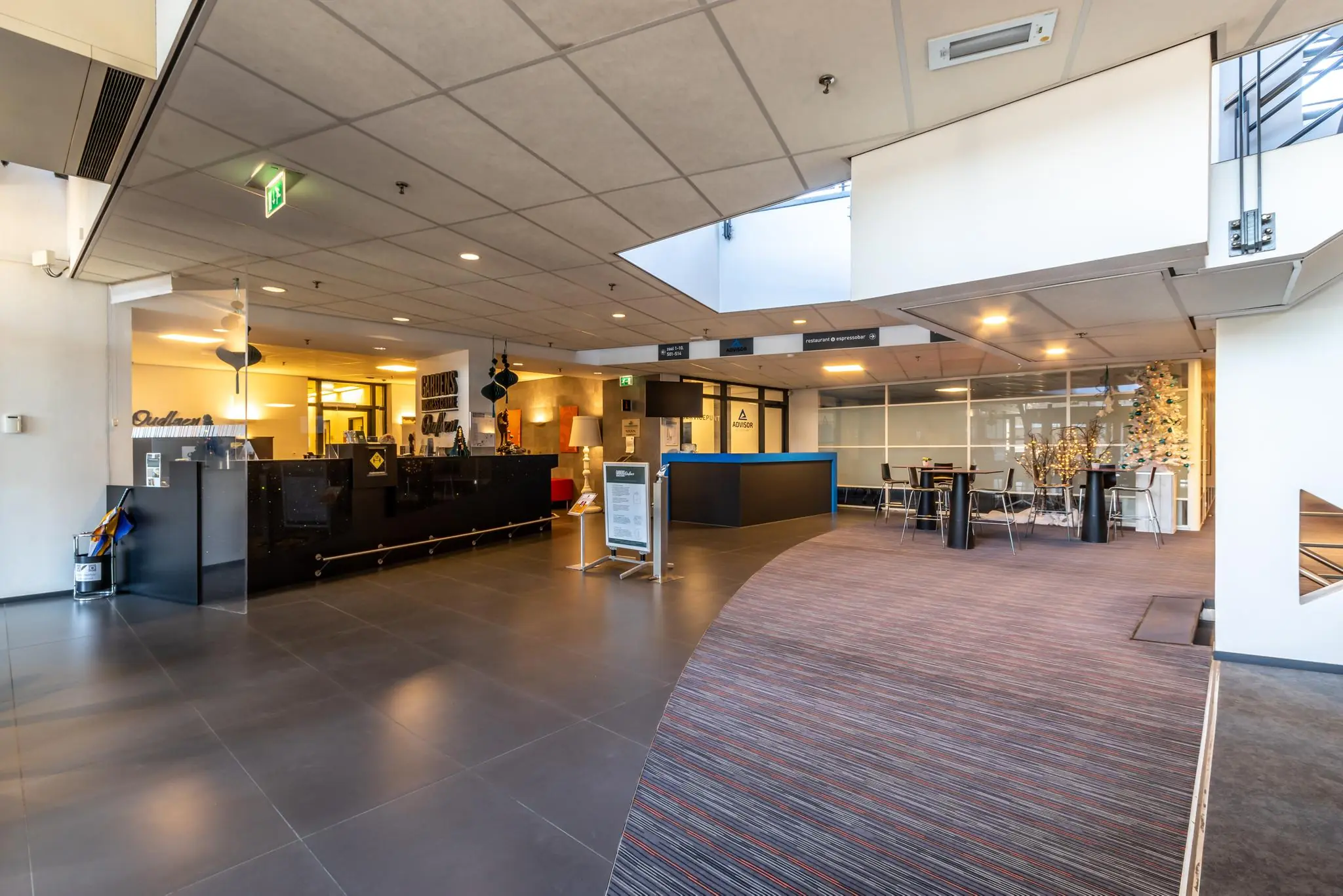 Moderne ontvangstruimte met een balie, zitgedeelte en kerstversiering in het gebouw aan de Oudlaan.
