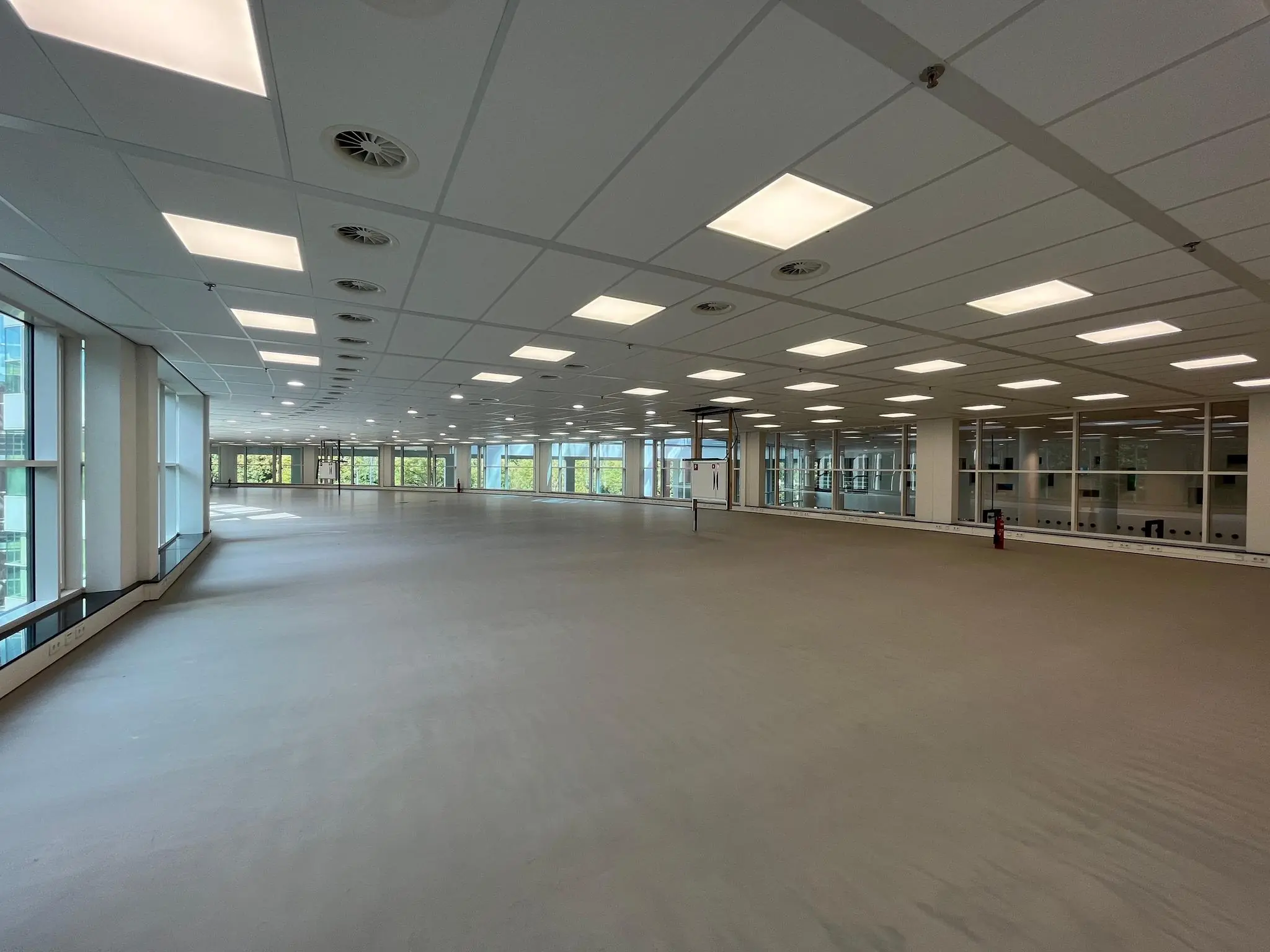 Leeg, modern kantoorverdieping aan de Newtonlaan met veel ramen en systeemplafond.
