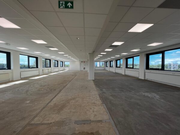 Leeg kantoorpand aan de Nevelgaarde met grote ramen en onafgewerkte vloer.