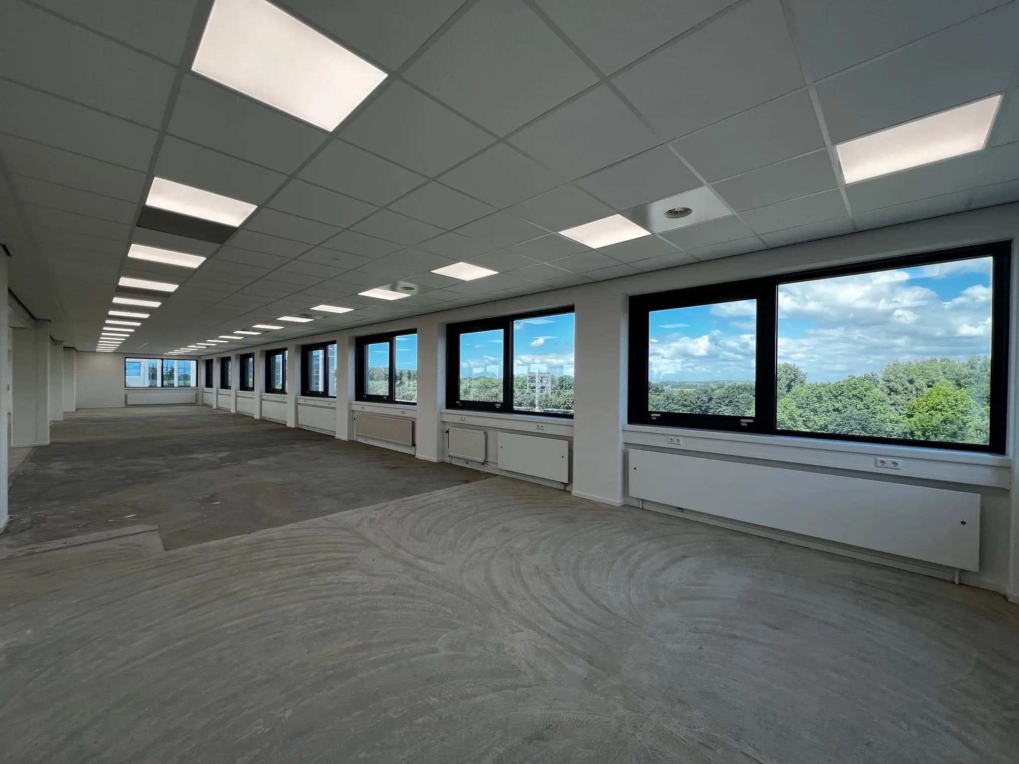 Leeg kantoorpand op Nevelgaarde met grote ramen en uitzicht op groene omgeving.