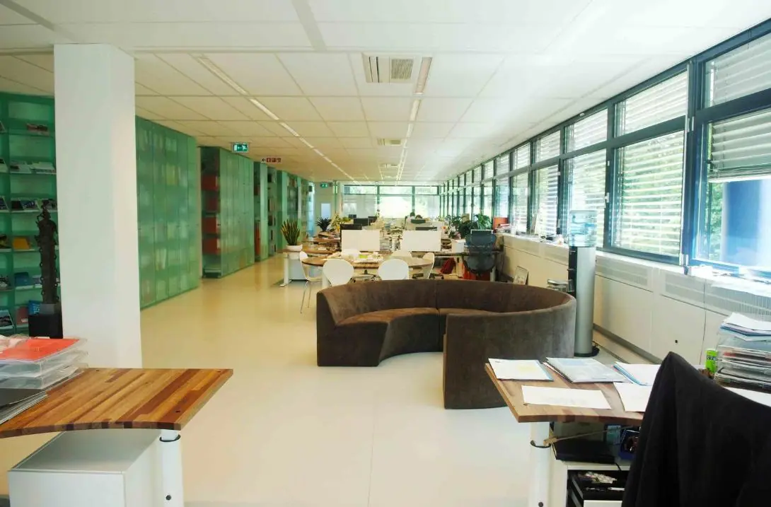 Moderne, lichte kantooruimte aan de Vreeswijksestraatweg met open werkplekken, grote ramen en een ronde zitbank.