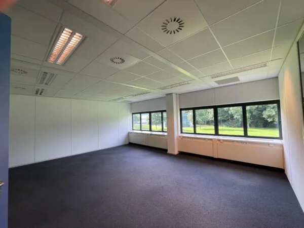 Lege kantoorruimte in het gebouw Sparrenheuvel met grote ramen en uitzicht op groen.