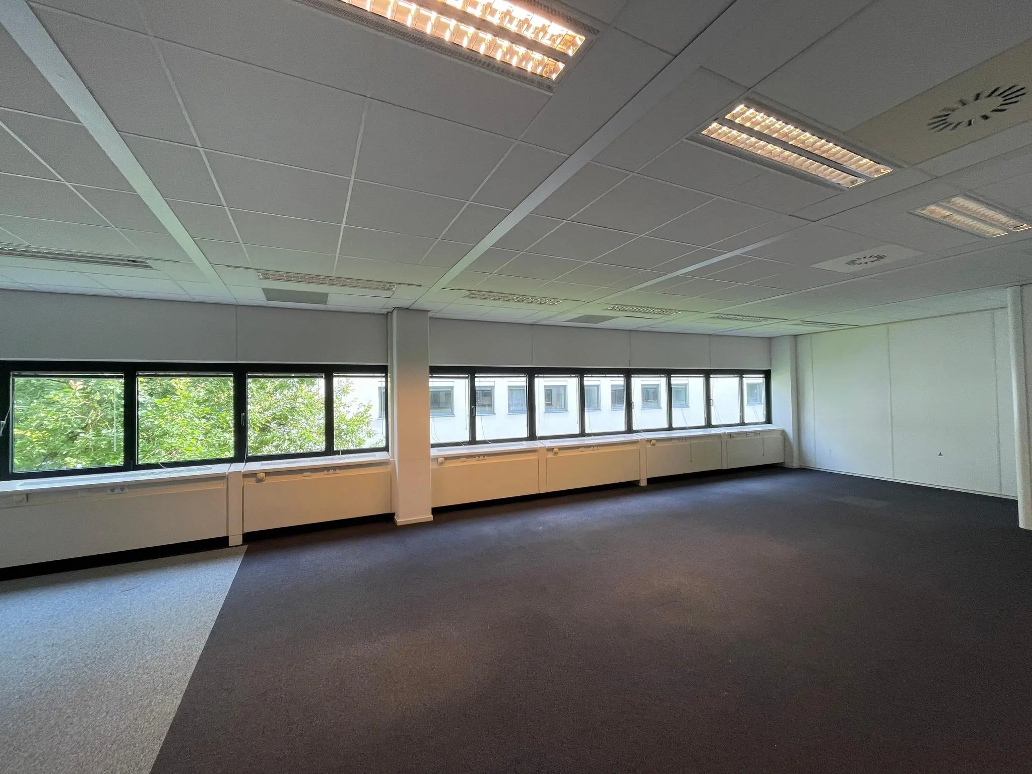 Leeg kantoor met systeemplafond en grote ramen in het gebouw Sparrenheuvel.