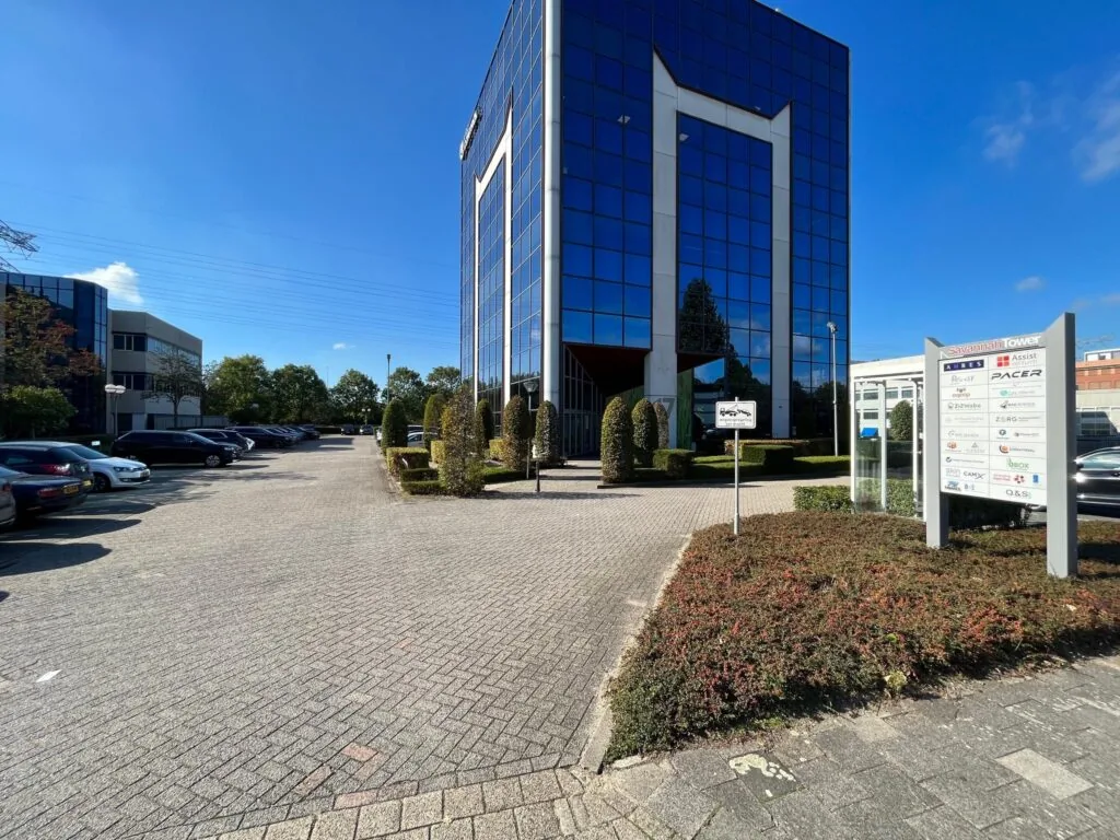Kantoorgebouw Savannah Tower met parkeerterrein en bedrijfsnamen op een informatiebord.