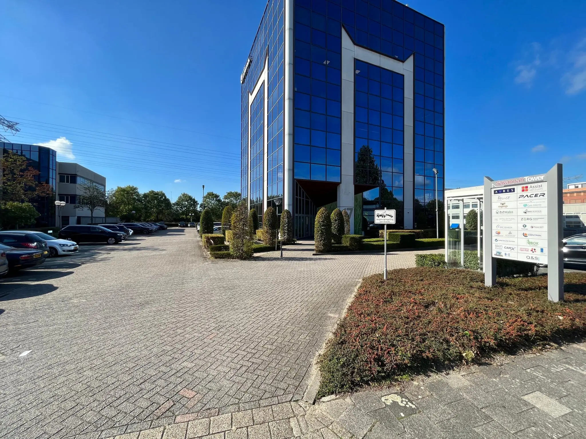 Kantoorgebouw Savannah Tower met parkeerterrein en bedrijfsnamen op een informatiebord.