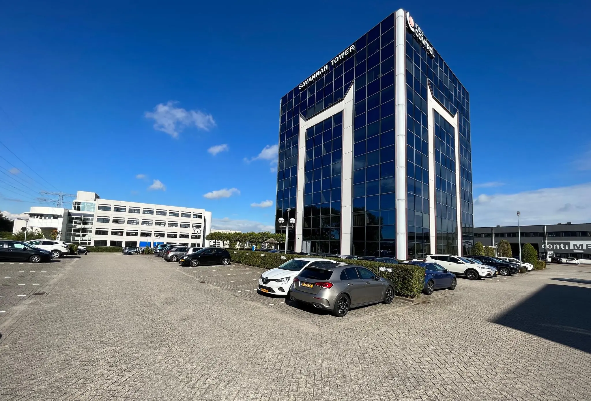 Kantoorcomplex Savannah Tower met omliggende parkeerplaats en meerdere geparkeerde auto's op een zonnige dag.