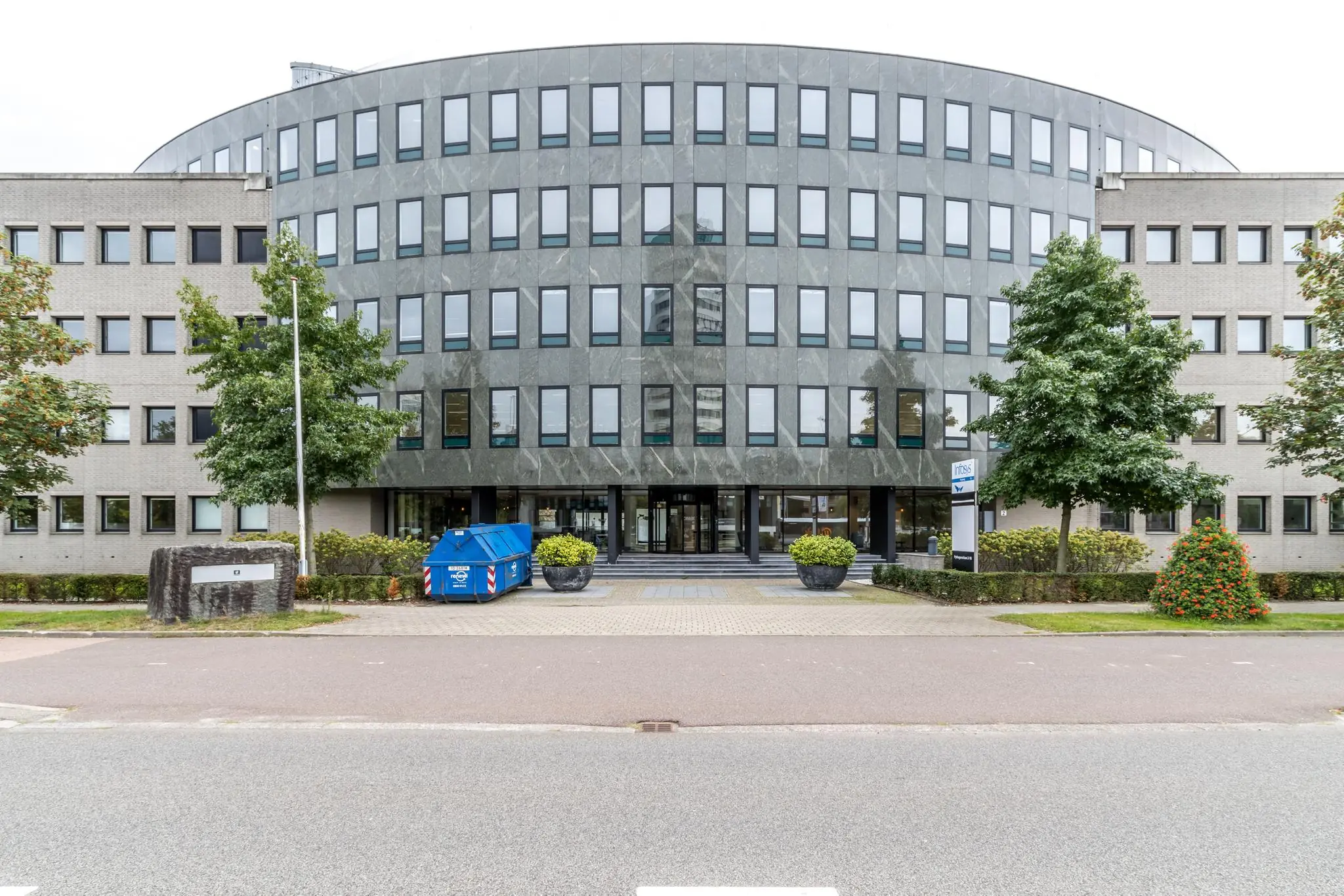 Kantoorgebouw aan de Pythagoraslaan met een moderne gevel en een blauwe afvalcontainer voor de ingang.
