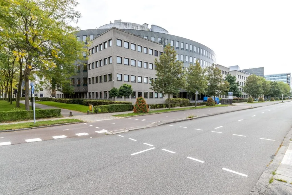 Kantoorgebouw aan de Pythagoraslaan in Utrecht met groene bomen en een lege straat op de voorgrond.