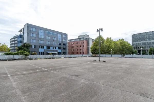 Leeg parkeerterrein aan de Pythagoraslaan met omliggende kantoorgebouwen en bomen.