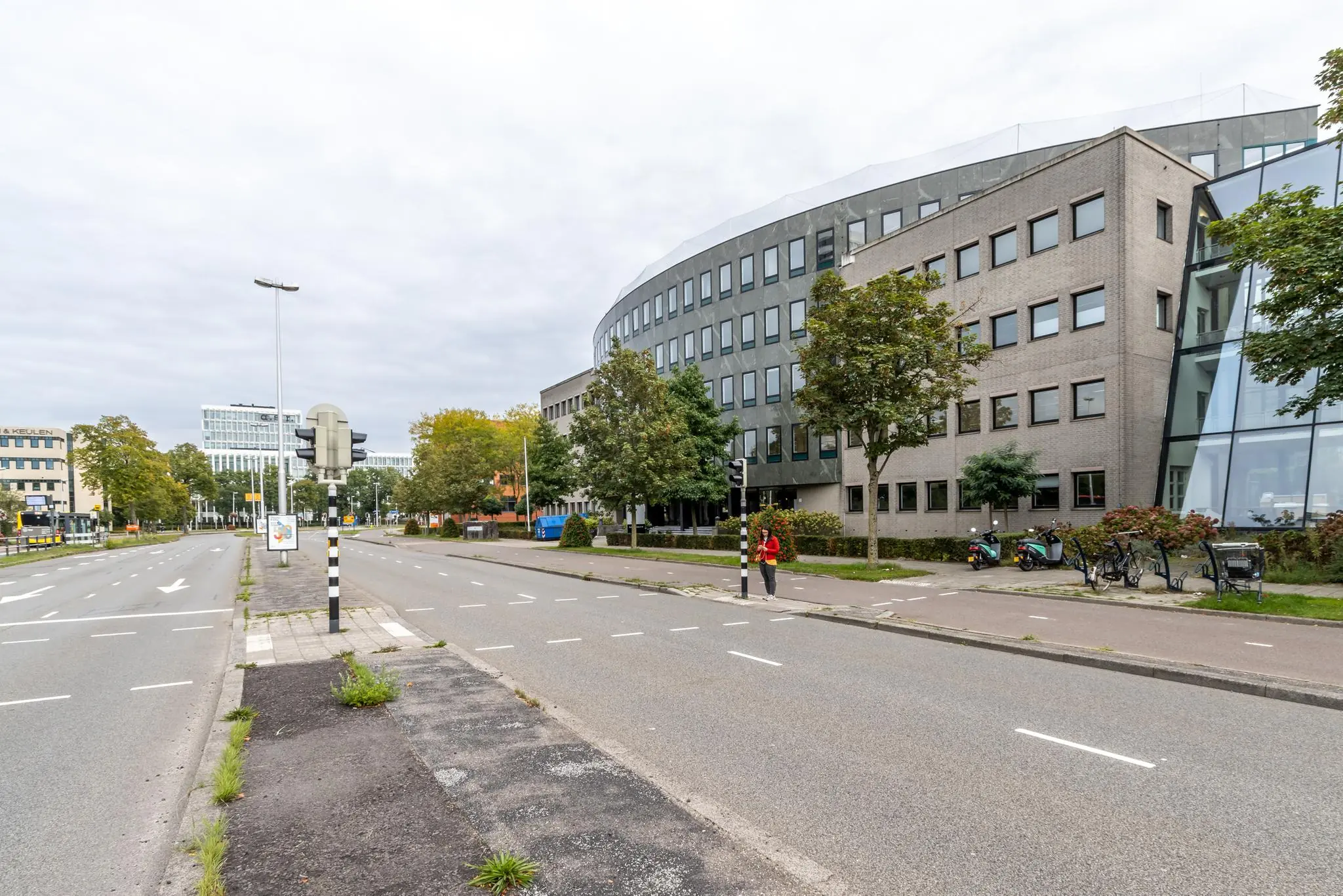 Straatbeeld van de Pythagoraslaan in Utrecht met kantoorgebouwen, bomen en een fietspad.