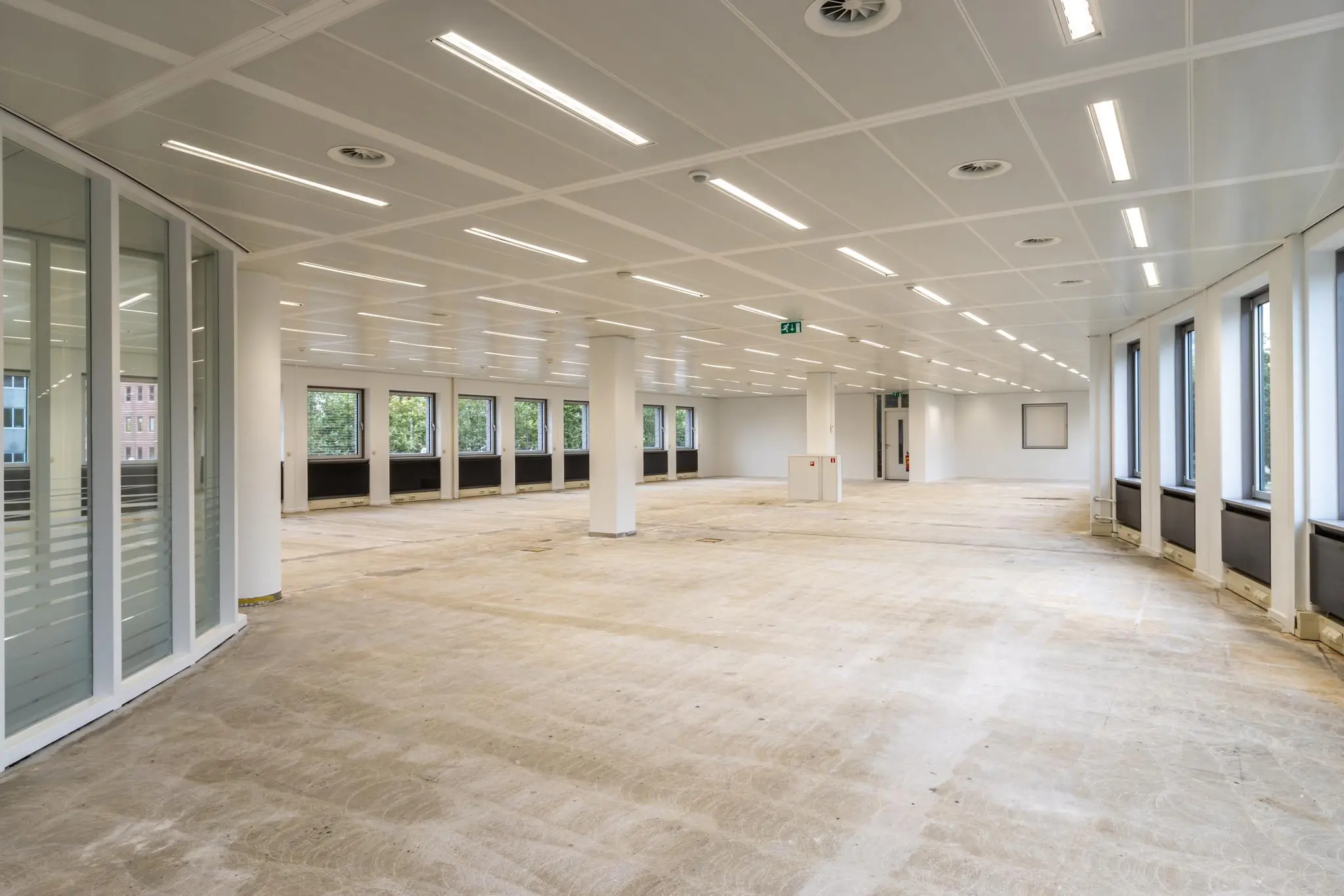 Leeg kantoorpand aan de Pythagoraslaan met grote ramen en systeemplafondverlichting.