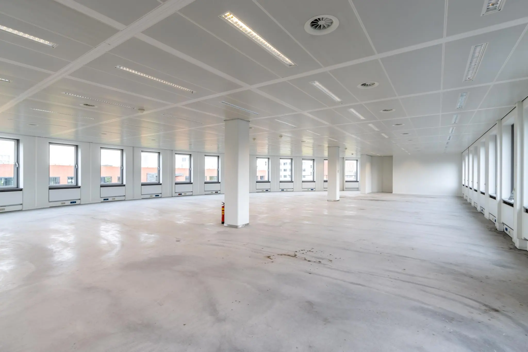 Leeg kantoorpand aan de Pythagoraslaan met veel ramen en witte wanden.
