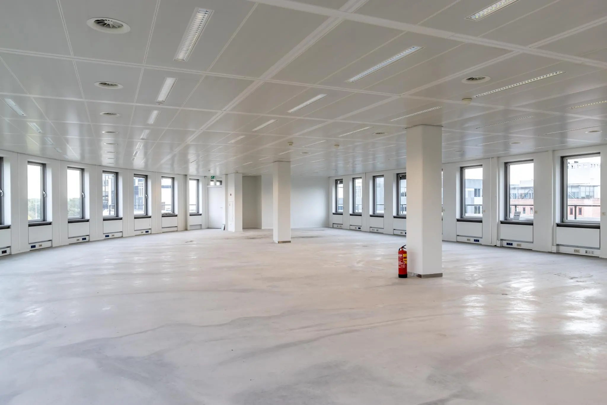 Lege kantoorruimte aan de Pythagoraslaan met grote ramen en strak wit plafond.