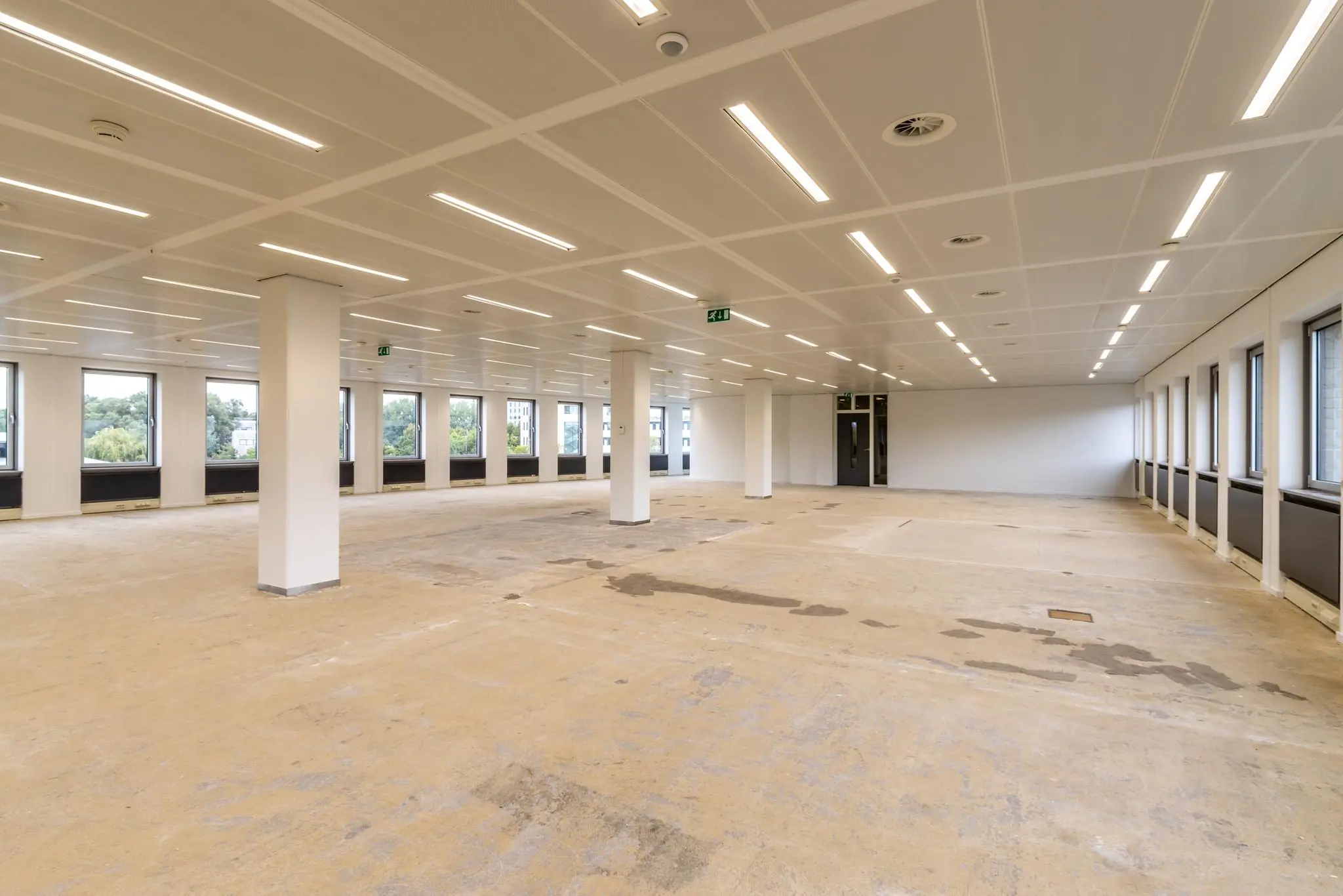 Leeg kantoorpand aan de Pythagoraslaan met systeemplafond, pilaren en grote ramen.