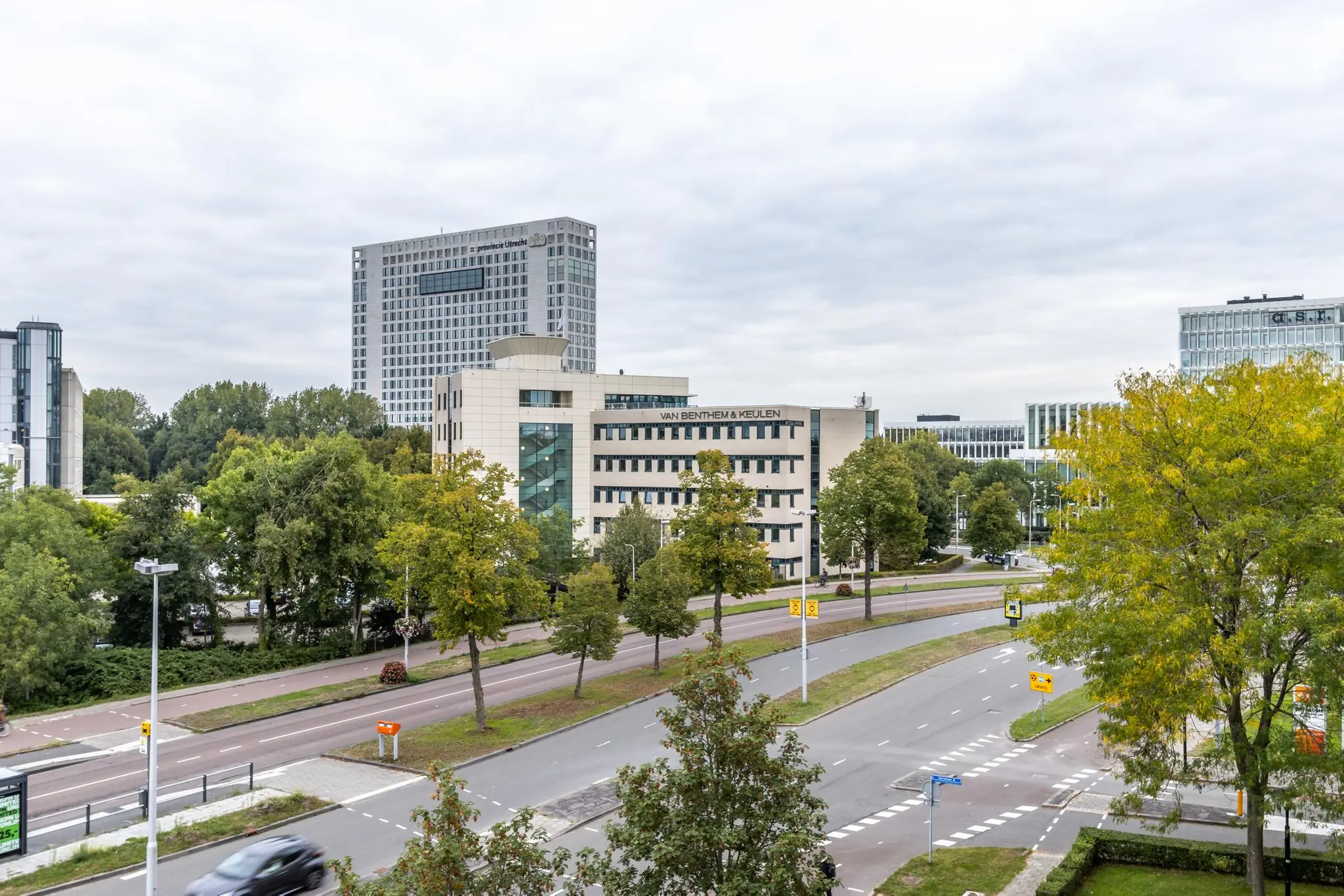 Kantoorgebouwen aan de Pythagoraslaan in Utrecht, omringd door groen en wegen met voorbijrijdend verkeer.