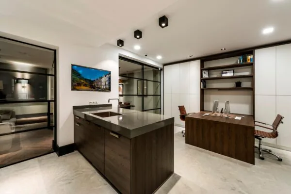 Modern kantoorinterieur aan de Emmastraat met een houten bureau, ingebouwde kasten, keukeneiland en strakke glazen wanden.
