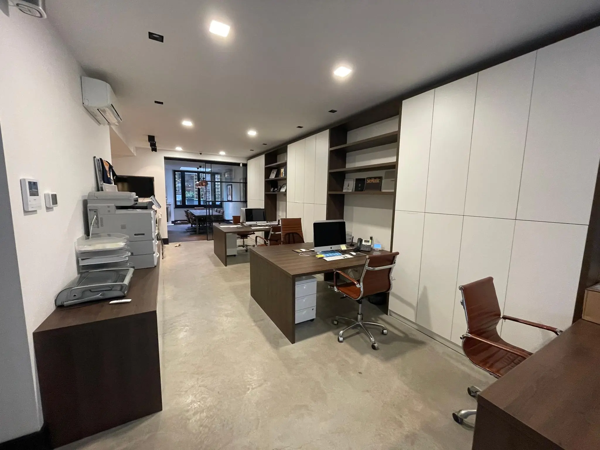 Modern ingericht kantoor aan de Emmastraat met houten bureaus, kastenwand en open werkruimte.