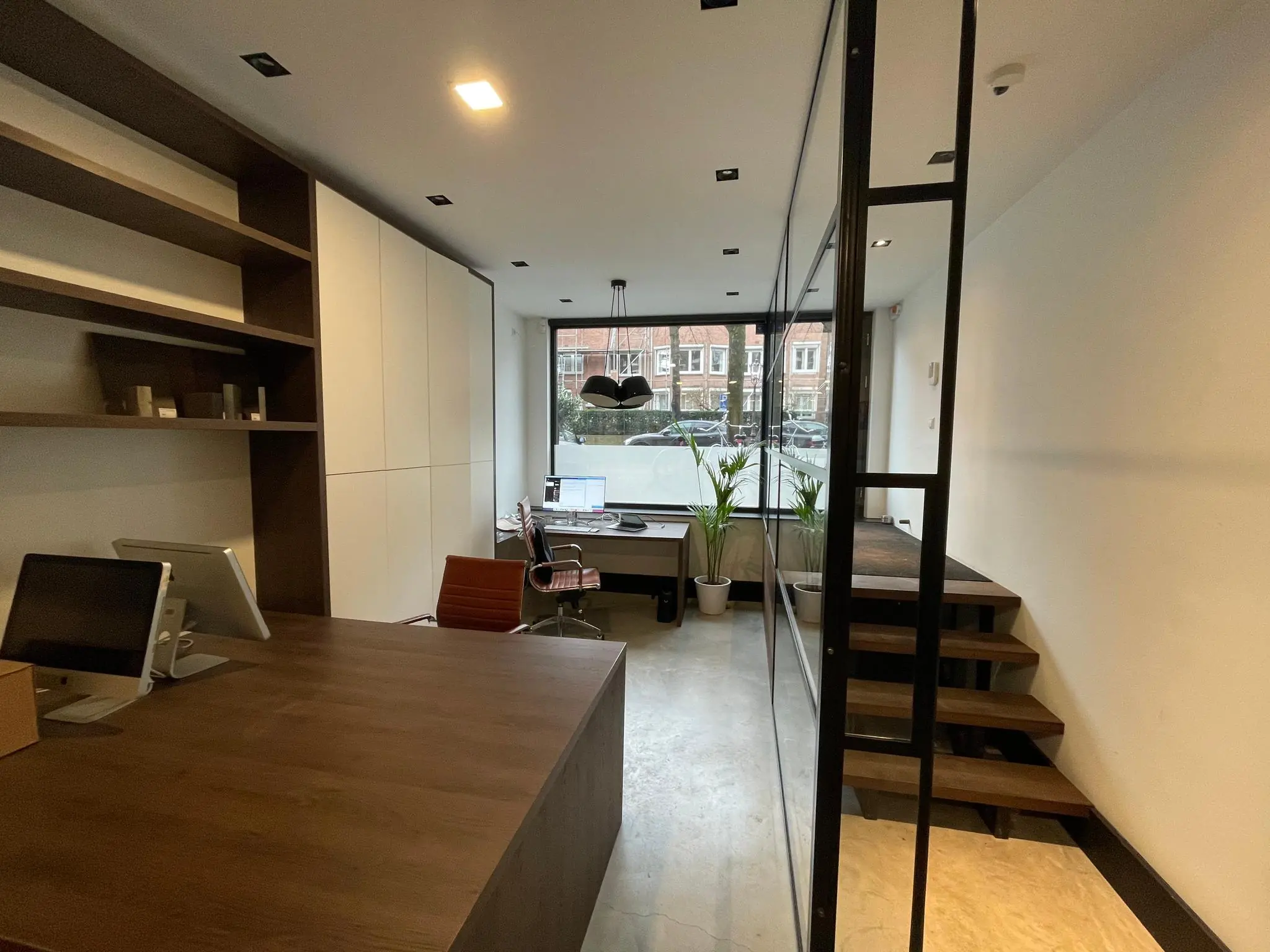 Modern kantoorinterieur aan de Emmastraat met houten meubels, glazen wand en uitzicht op de straat.