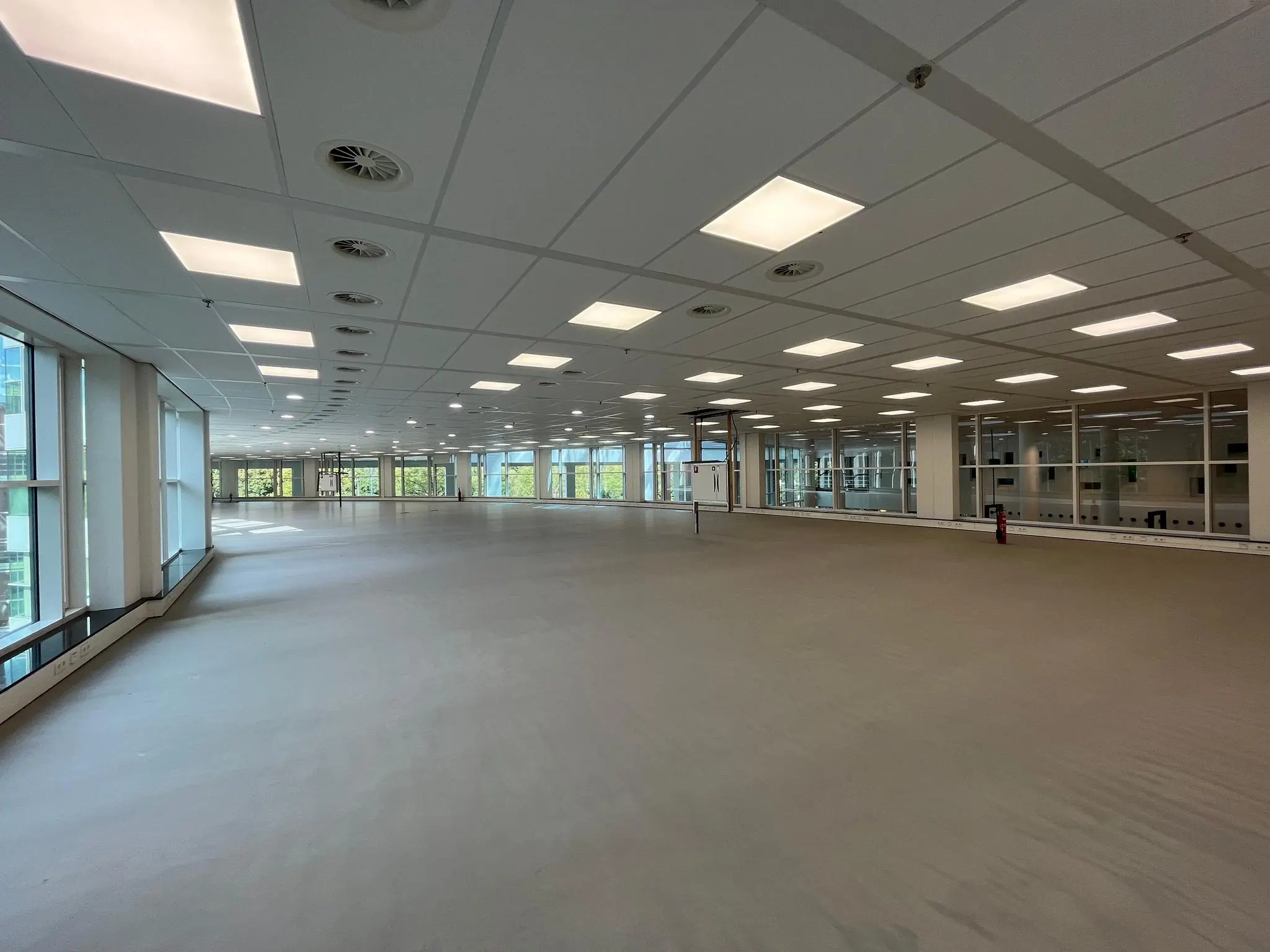 Leeg en modern kantoorpand aan de Newtonlaan met grote ramen en systeemplafond.