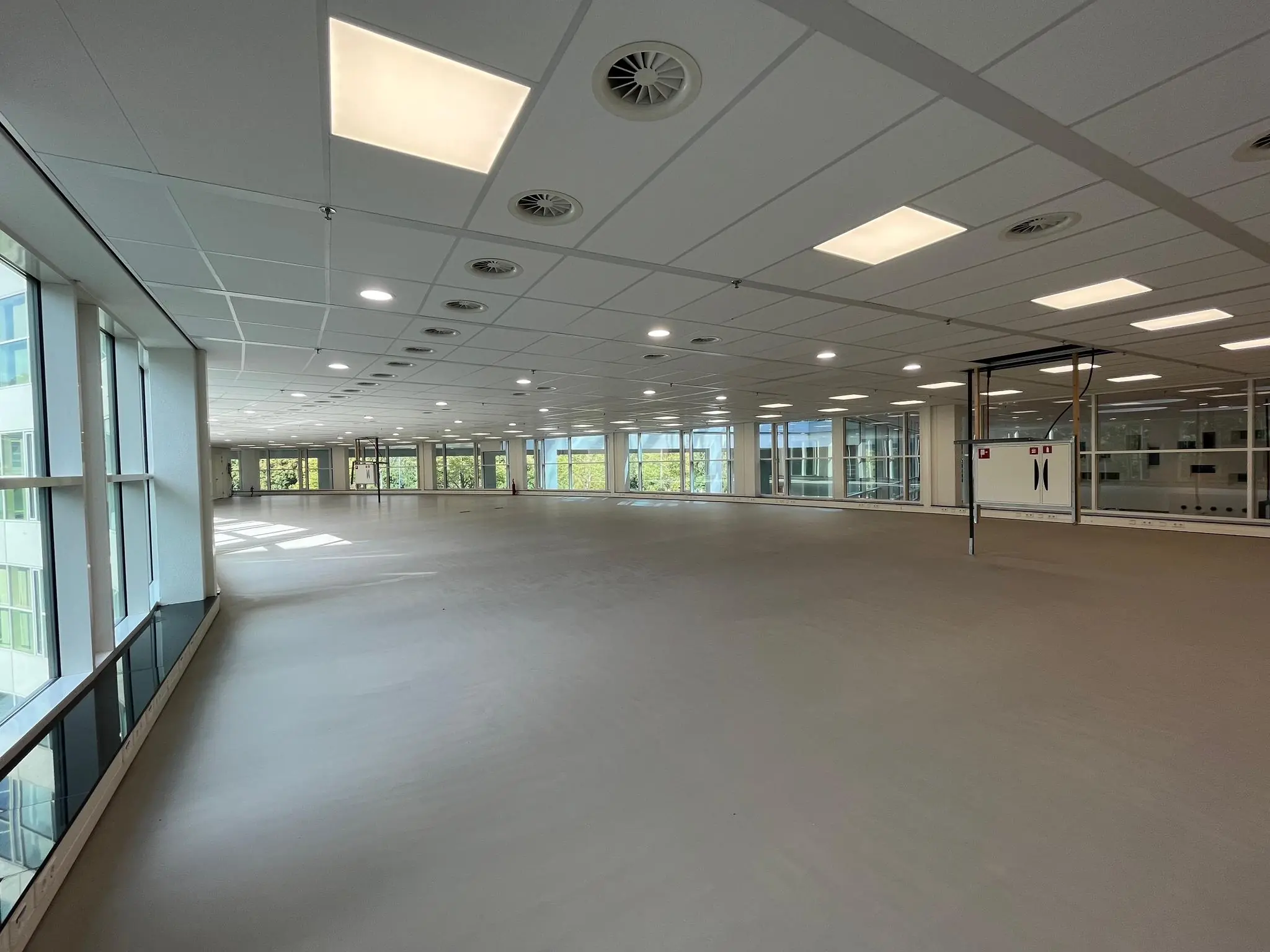 Leeg kantoorpand aan de Newtonlaan met grote ramen en systeemplafond.