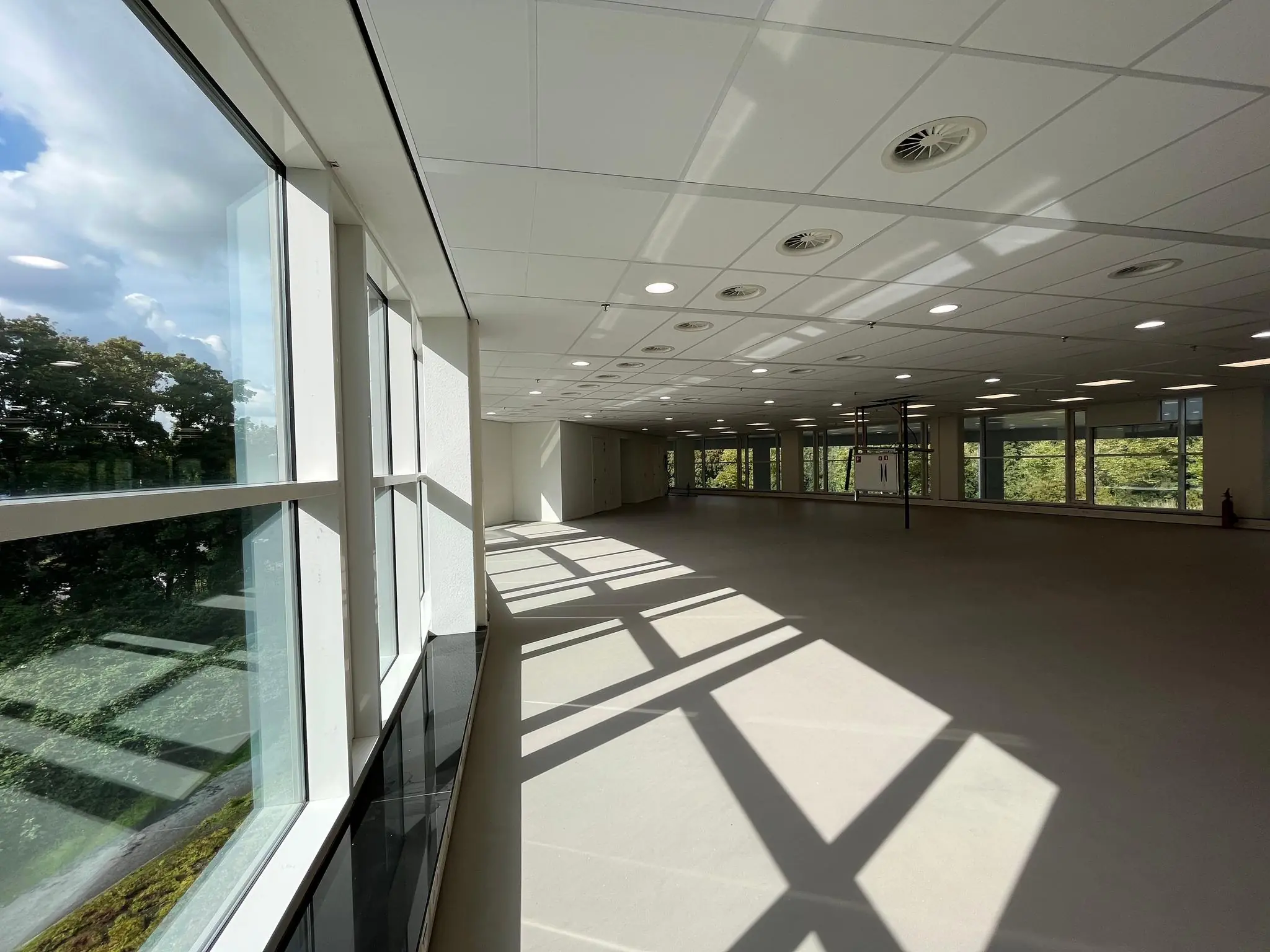 Lichte, lege kantoorruimte aan de Newtonlaan met grote ramen en uitzicht op groen.