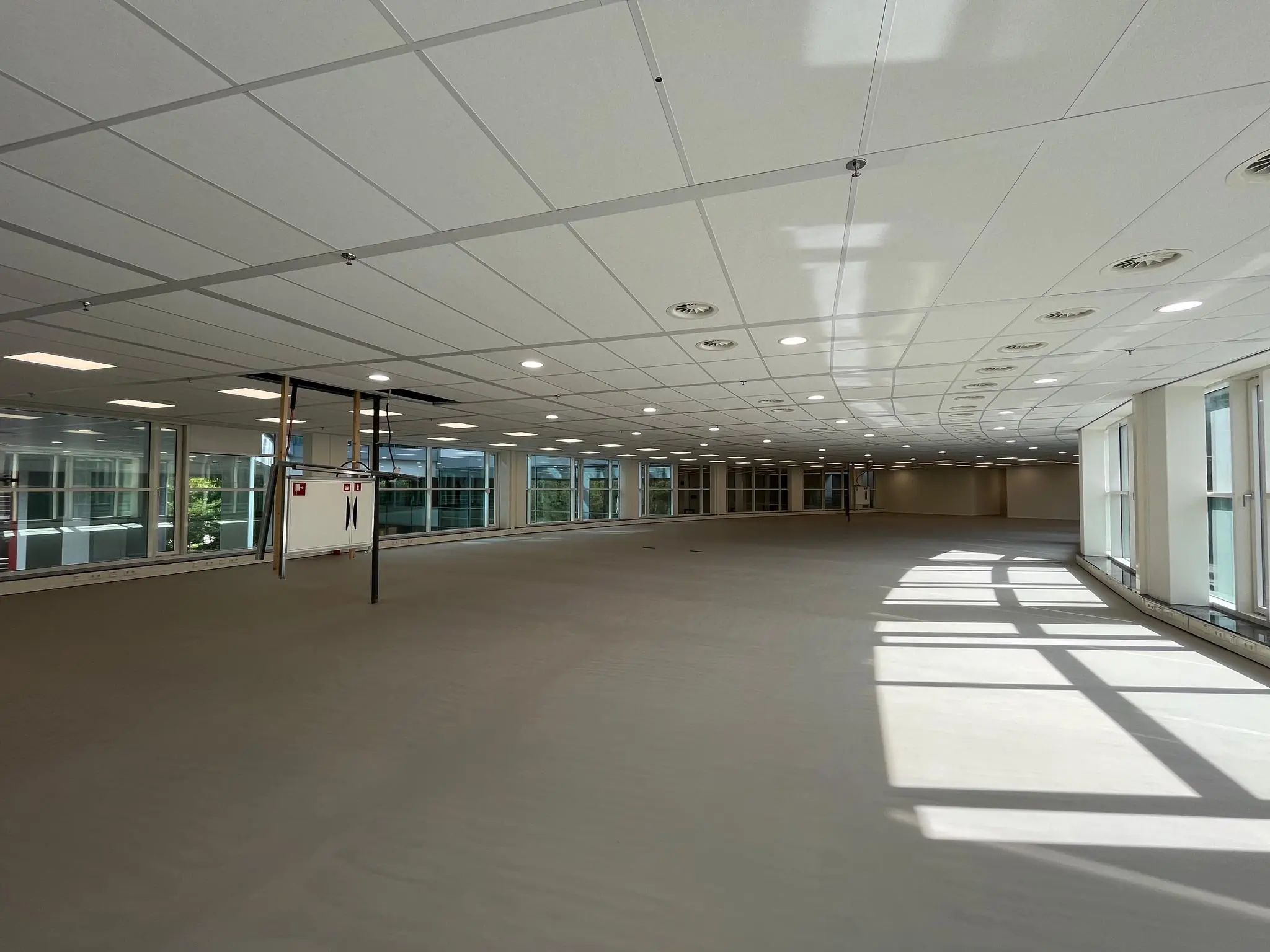 Lichte, lege kantoorruimte aan de Newtonlaan met grote ramen en systeemplafond.