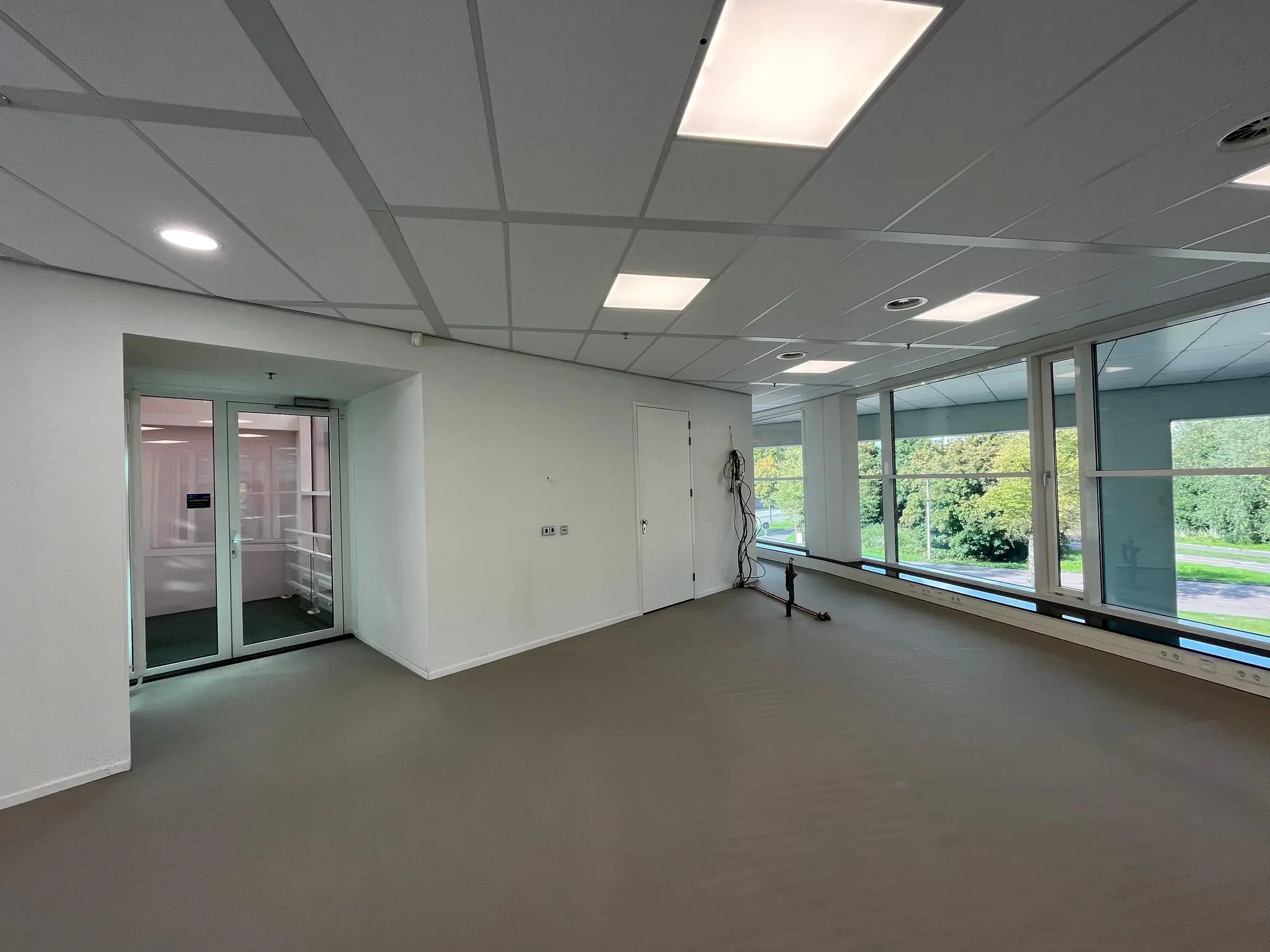 Leeg kantoorpand aan de Newtonlaan met grote ramen en systeemplafond.