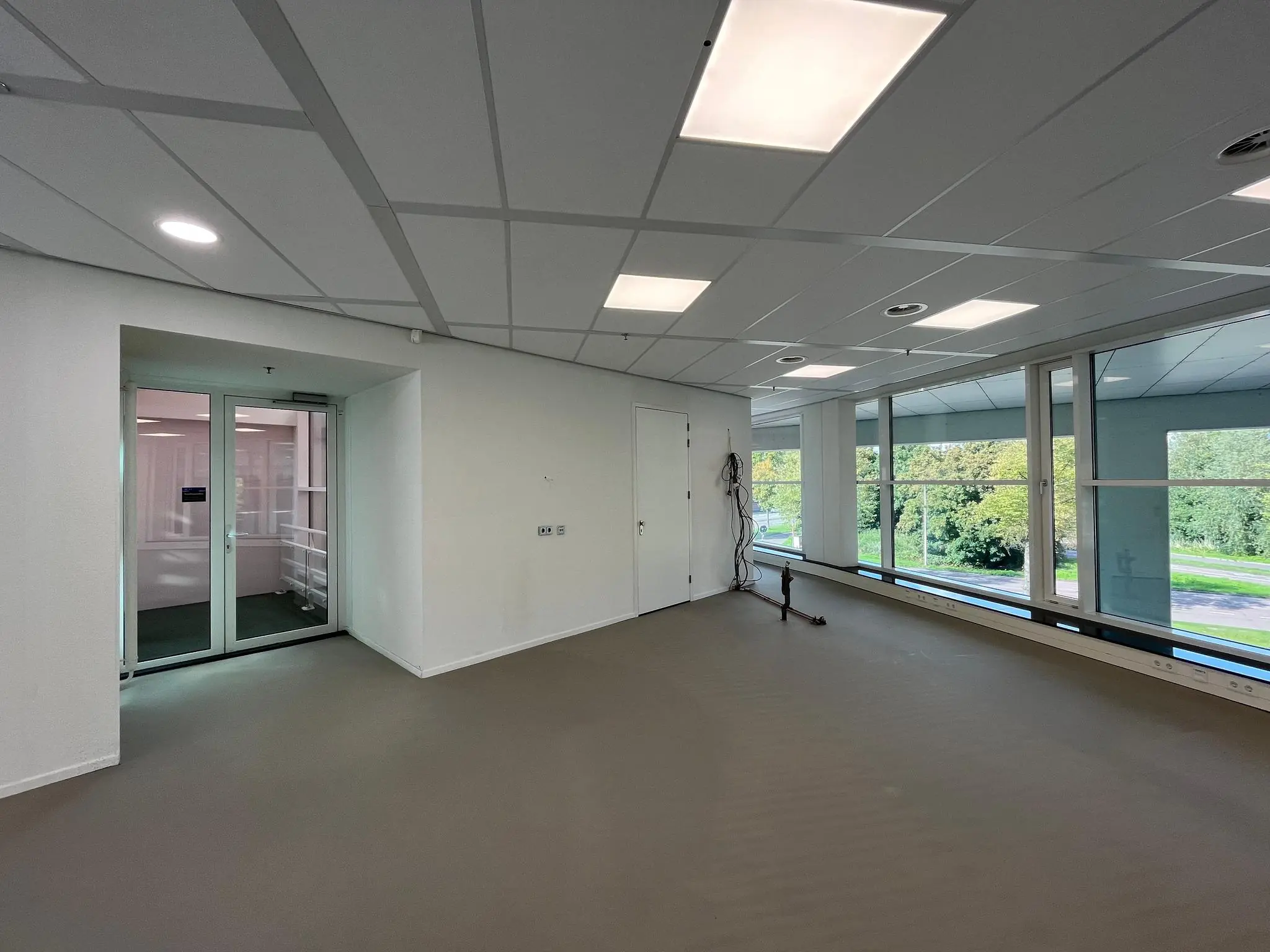 Leeg kantoorruimte aan de Newtonlaan met grote ramen en systeemplafond.