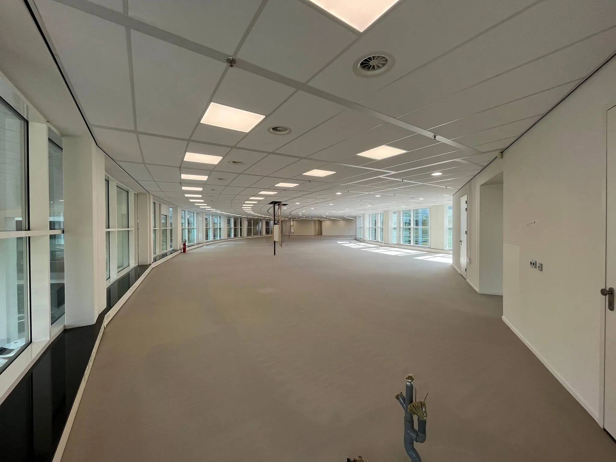 Leeg kantoorpand aan de Newtonlaan met grote ramen en systeemplafond.