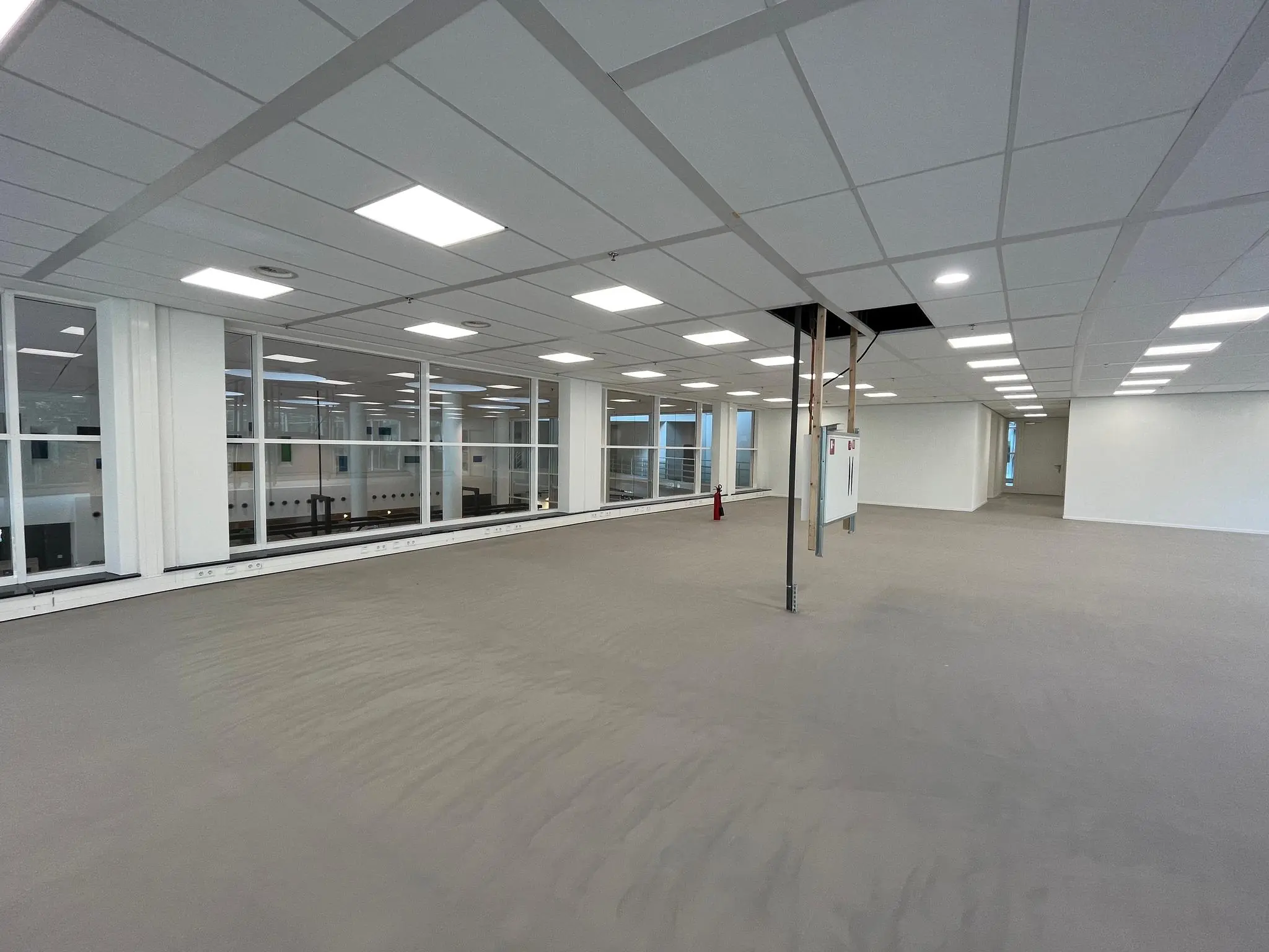 Leeg kantoorruimte op de Newtonlaan met systeemplafond en grote ramen naar een onderliggende verdieping.