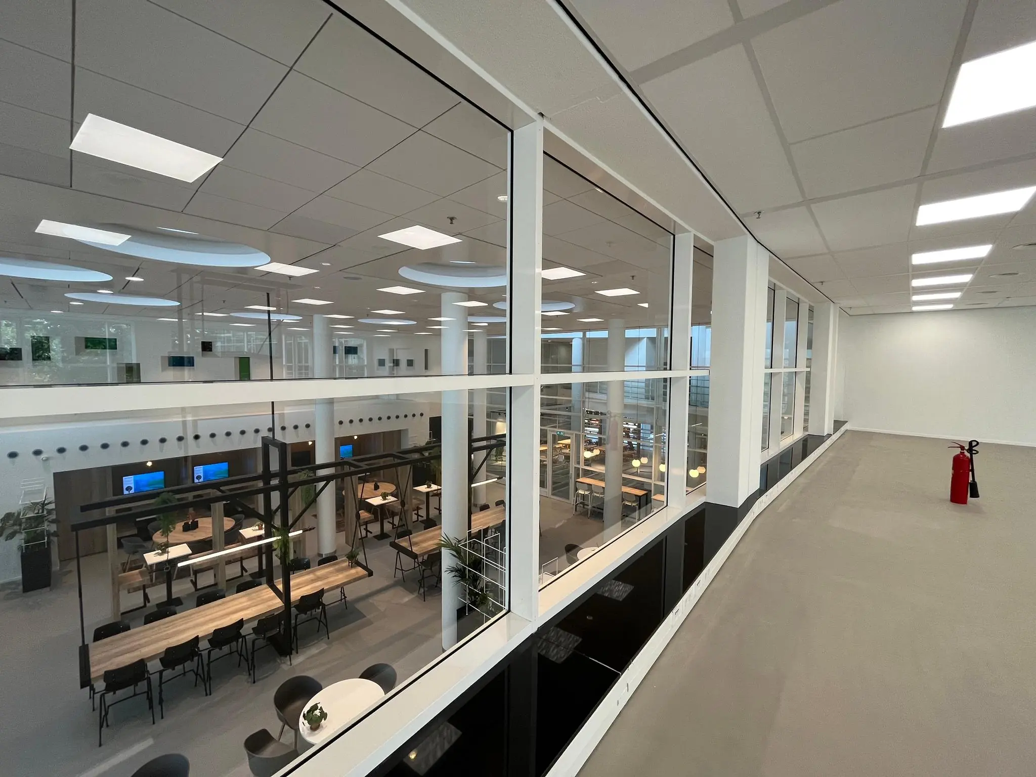 Modern kantoorinterieur aan de Newtonlaan met uitzicht op een open werkruimte met bureaus en vergadertafels.