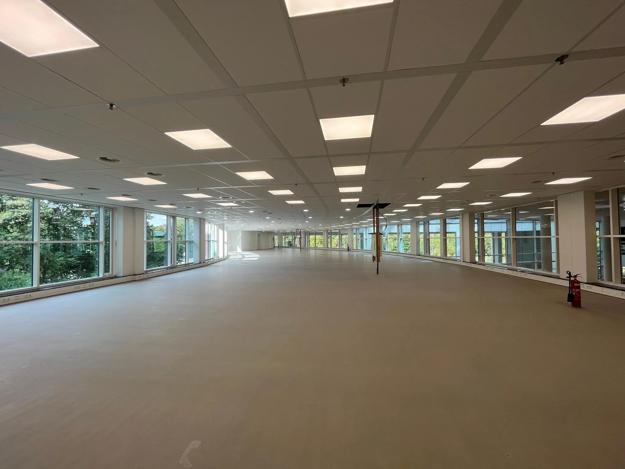 Leeg kantoorpand aan de Newtonlaan met grote ramen en systeemplafondverlichting.