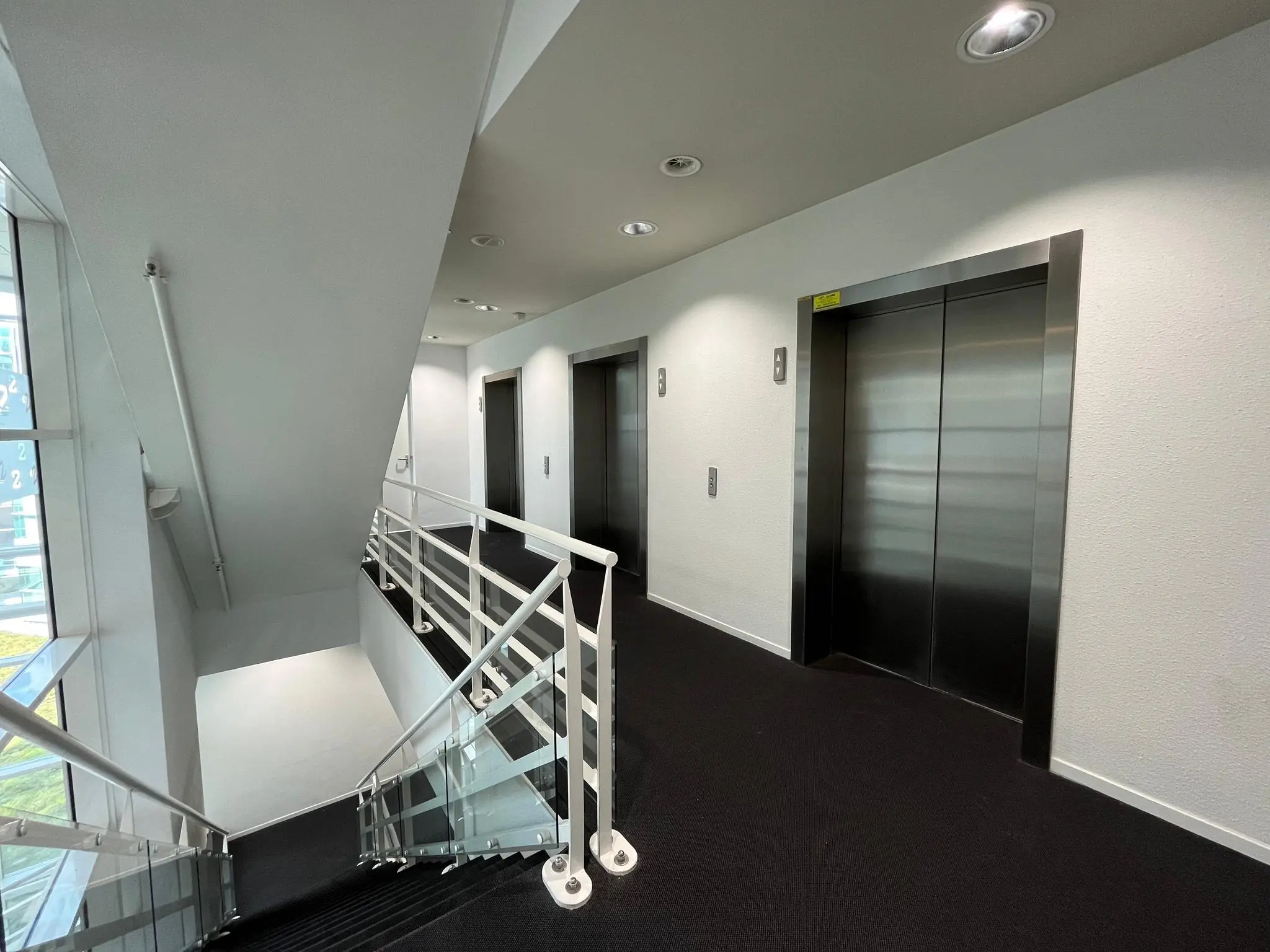 Moderne gang met drie liften en een trap bij Newtonlaan, goed verlicht en strak vormgegeven.