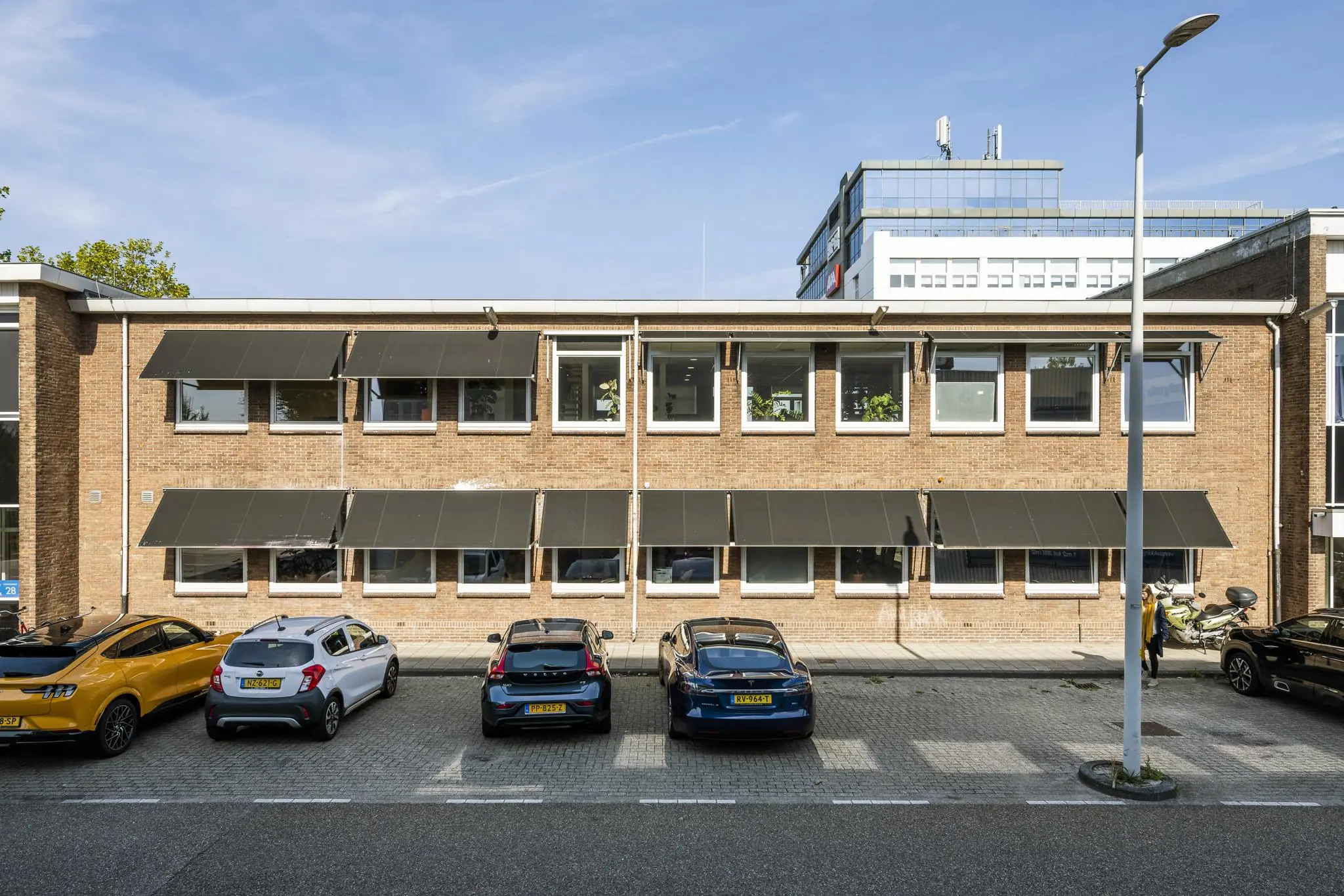 Vooraanzicht van een kantoorgebouw aan de Vliegtuigstraat met geparkeerde auto's ervoor.