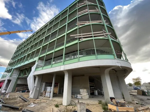 Gebouw in aanbouw aan de Cartesiusweg met groene gevel en ronde hoeken.