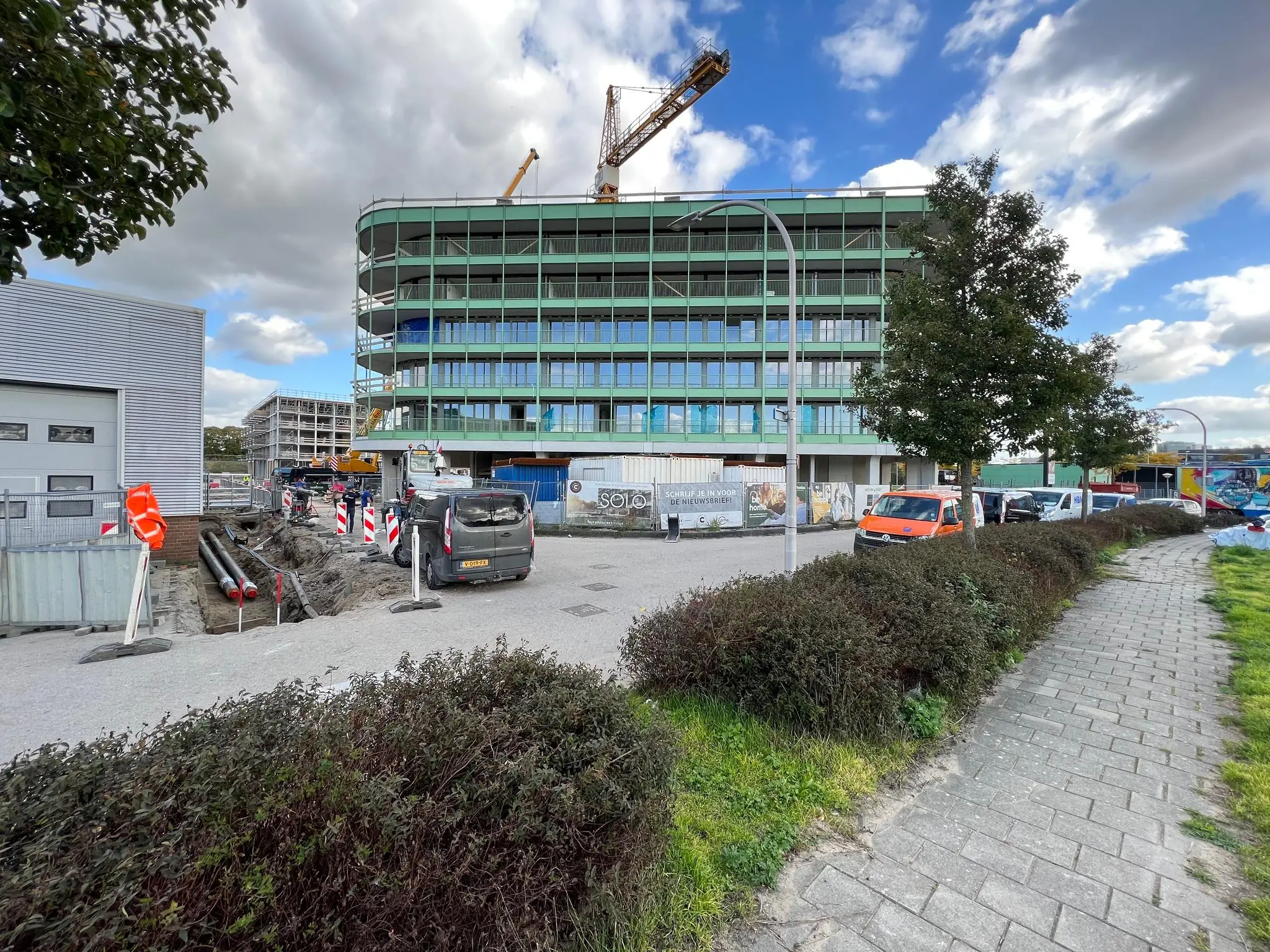 Bouwplaats aan de Cartesiusweg met een groot modern gebouw in aanbouw en werkzaamheden aan de weg.