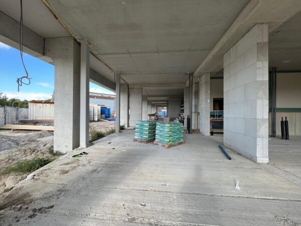 Een betonnen nieuwbouwconstructie aan de Cartesiusweg met stapels bouwmaterialen en zicht op de ruwbouw.