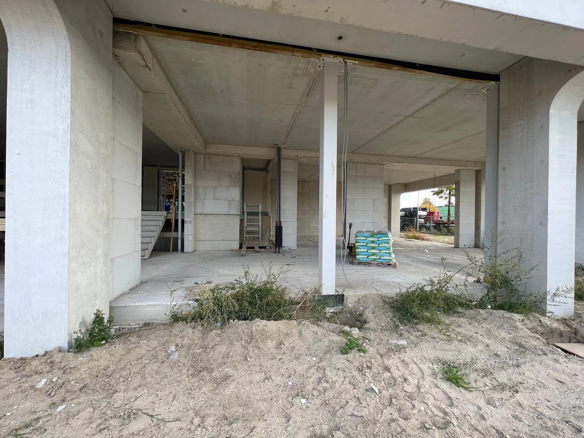 Open betonconstructie in aanbouw aan de Cartesiusweg met bouwmaterialen en zand op de voorgrond.