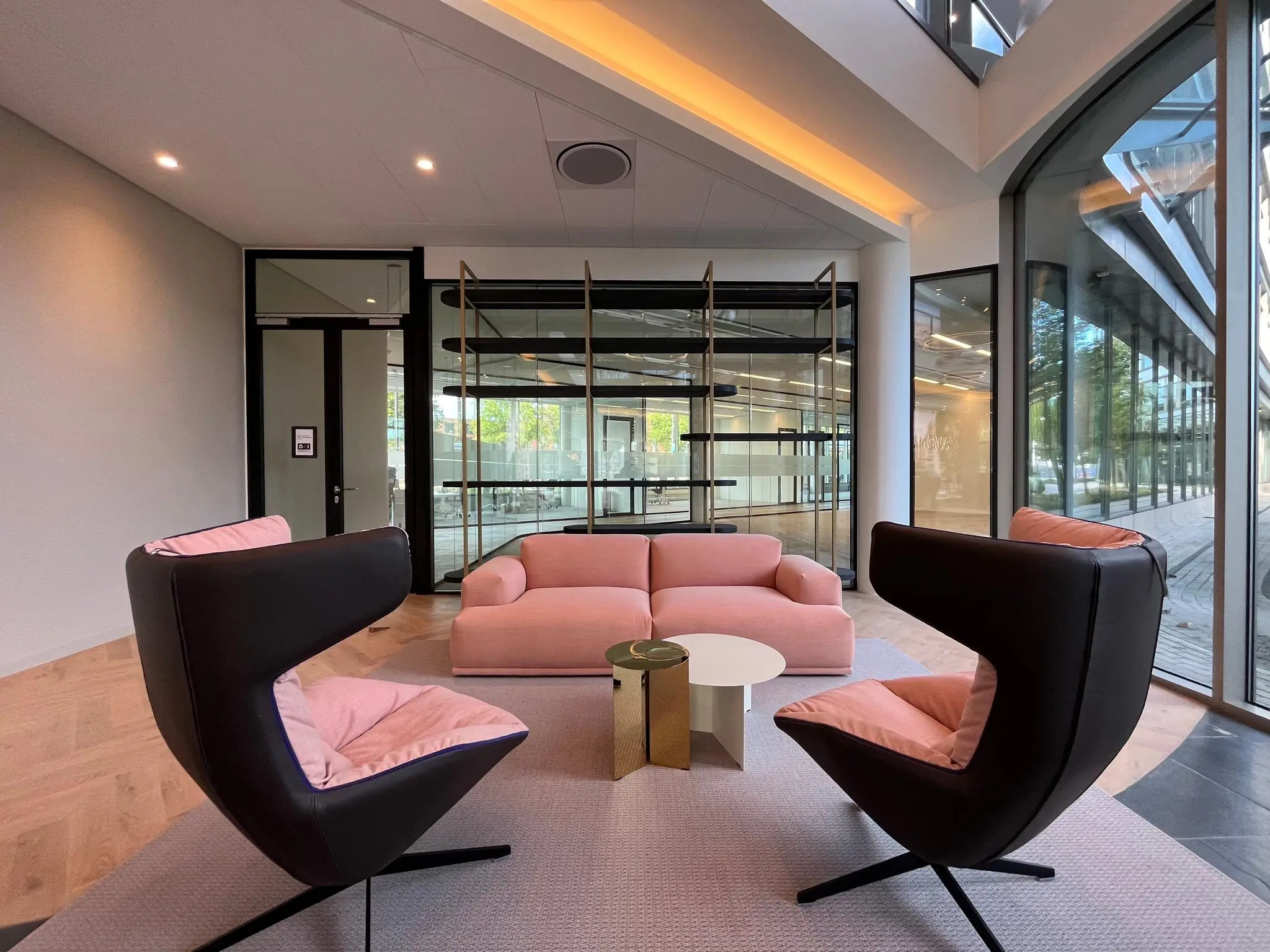 Moderne wachtruimte aan de Europalaan met roze zitmeubels, designstoelen en grote raampartijen.