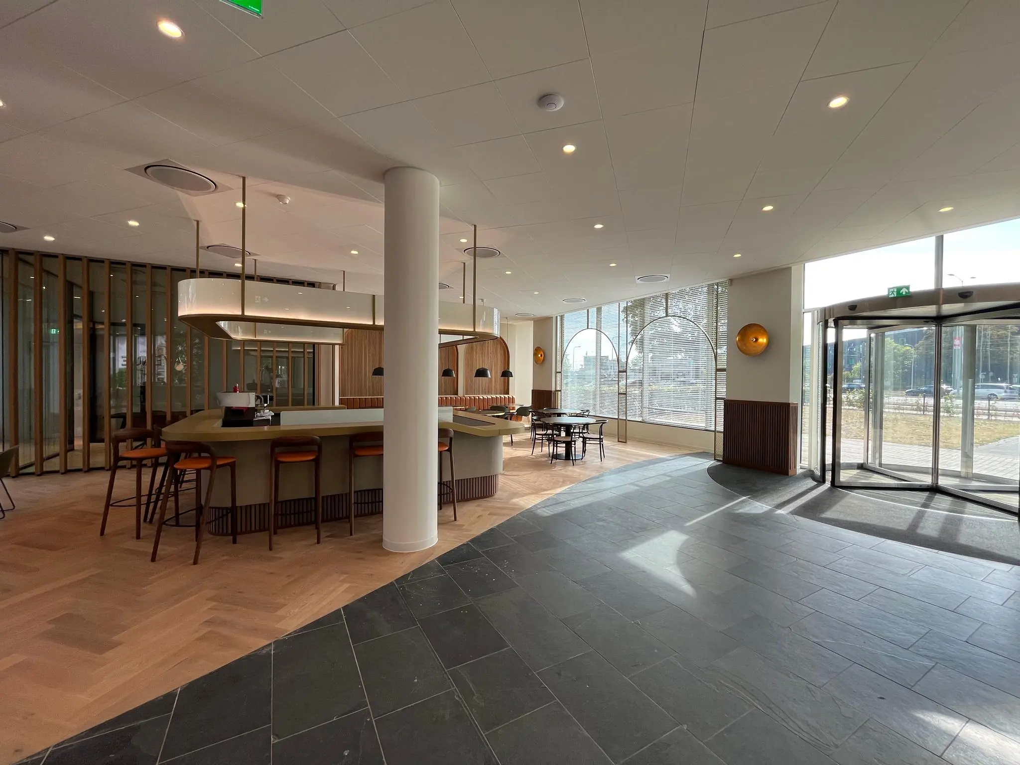 Moderne en lichte ontvangstruimte aan de Europalaan met een centrale bar, zithoek en een glazen draaideur.